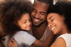 Three people embrace closely, eyes closed and smiling warmly in a tender, affectionate moment.