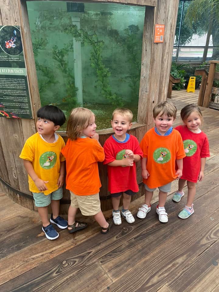 A group of young children are standing in front of a fish tank.