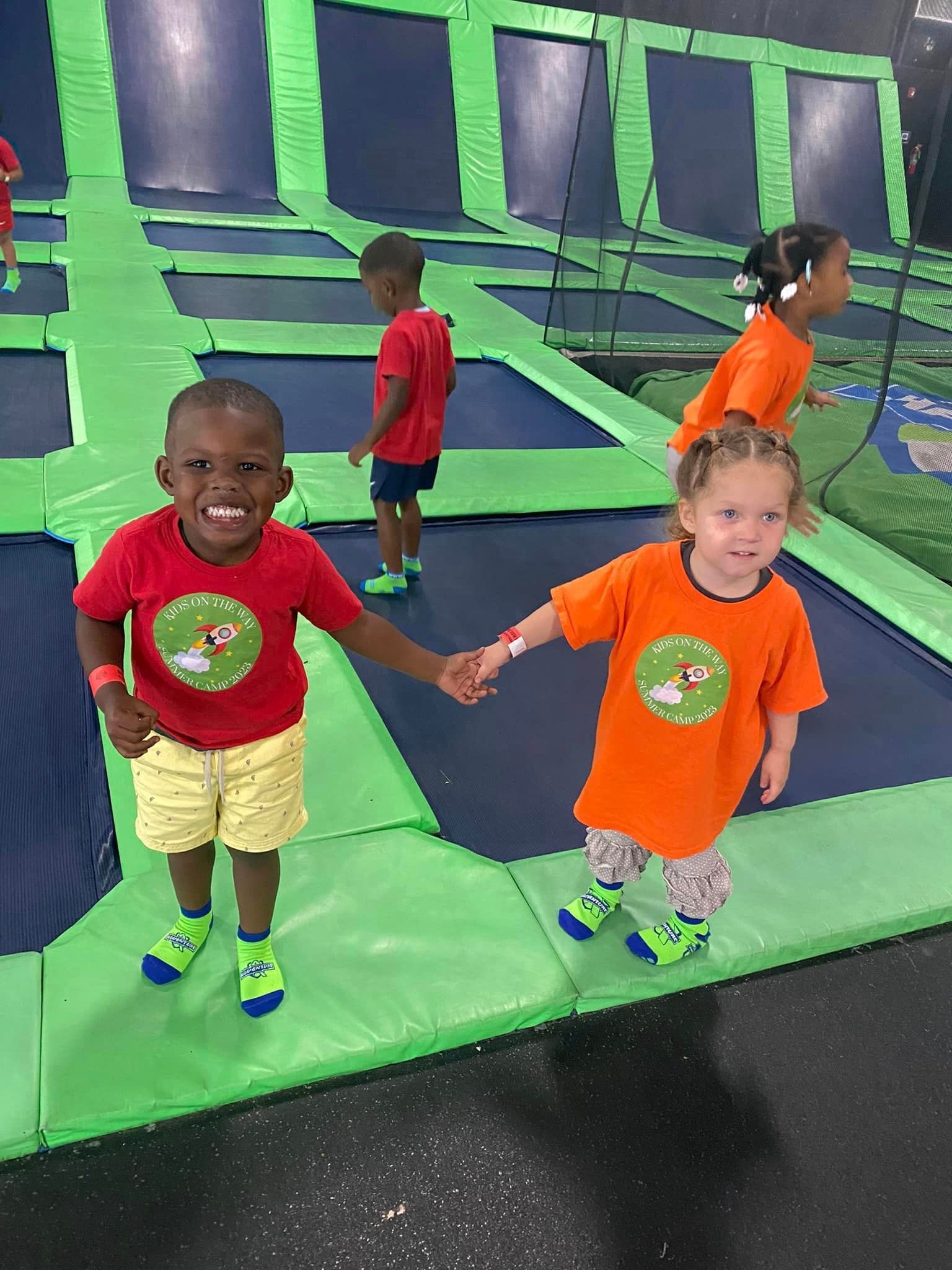 A boy and a girl are holding hands on a trampoline.
