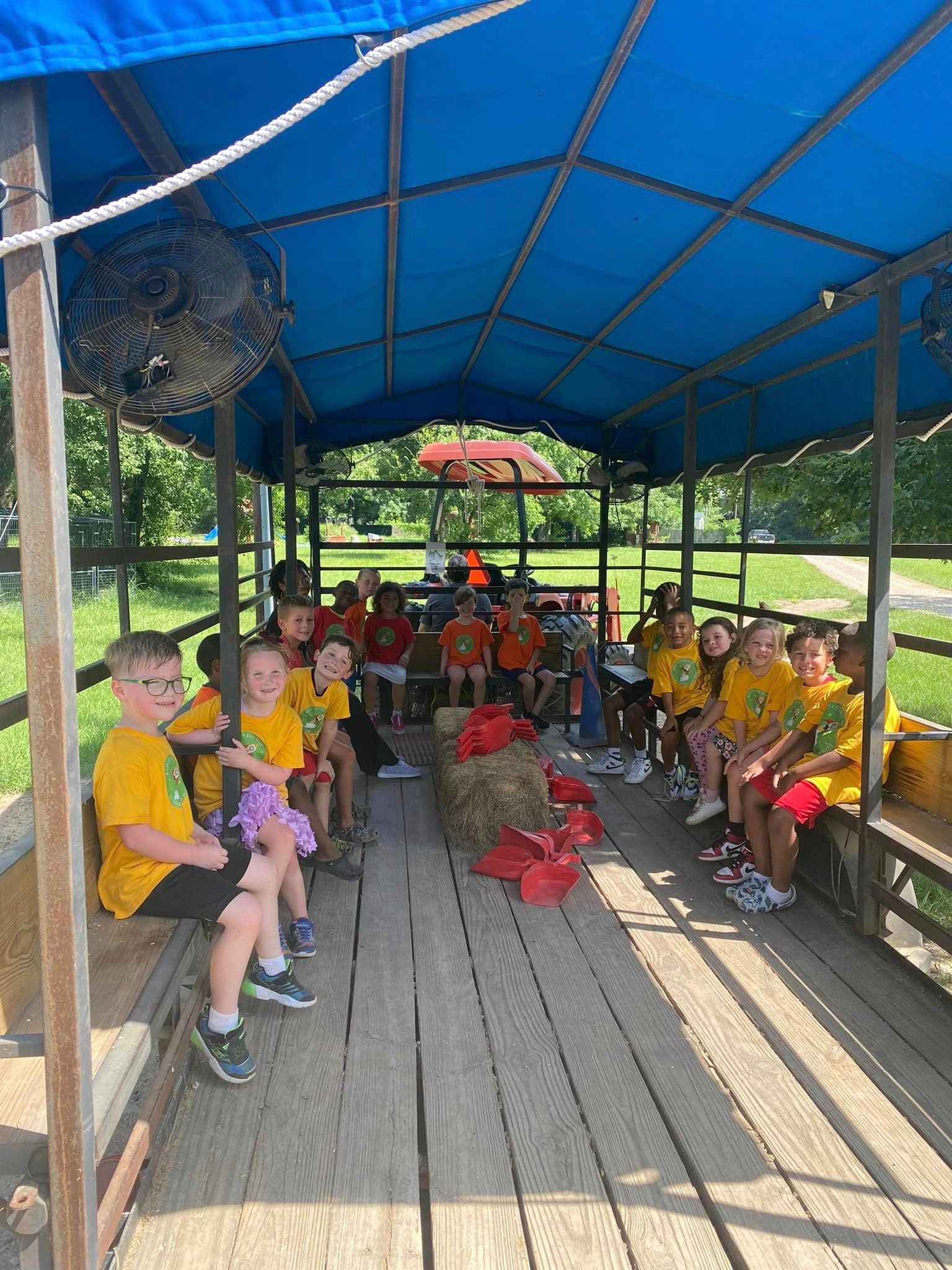 A group of children are sitting on a boat under a blue canopy.