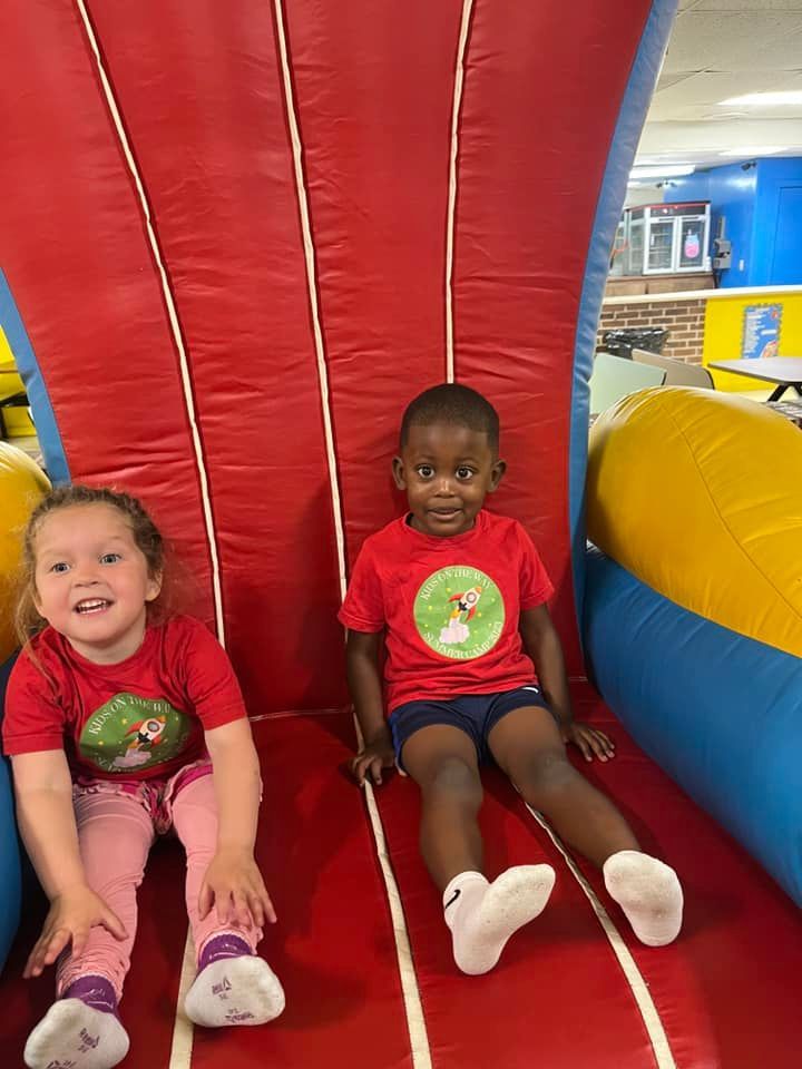 A boy and a girl are sitting on a bouncy house.