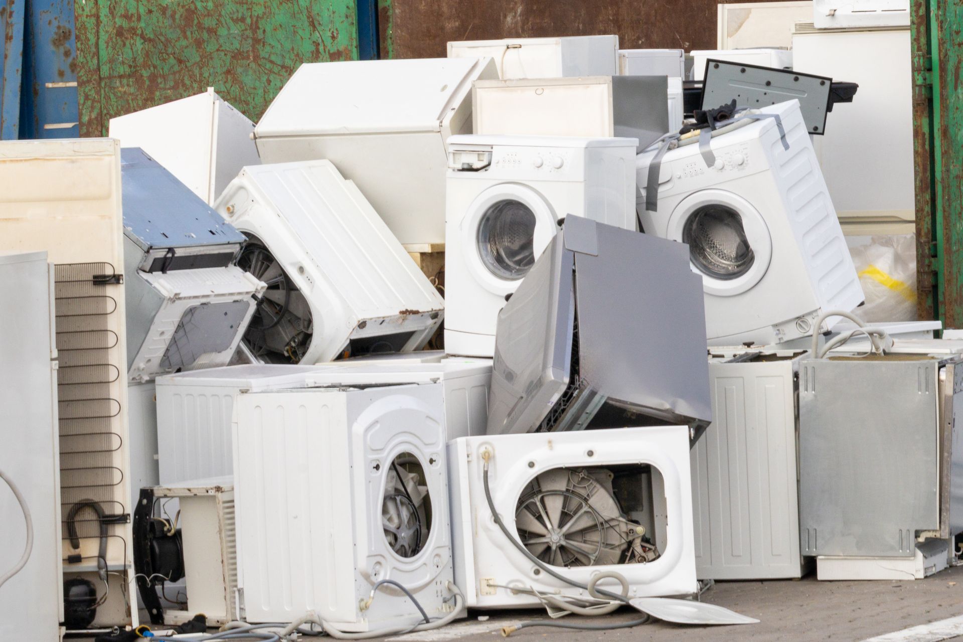 Pile of discarded white washing machines and appliances in a scrapyard