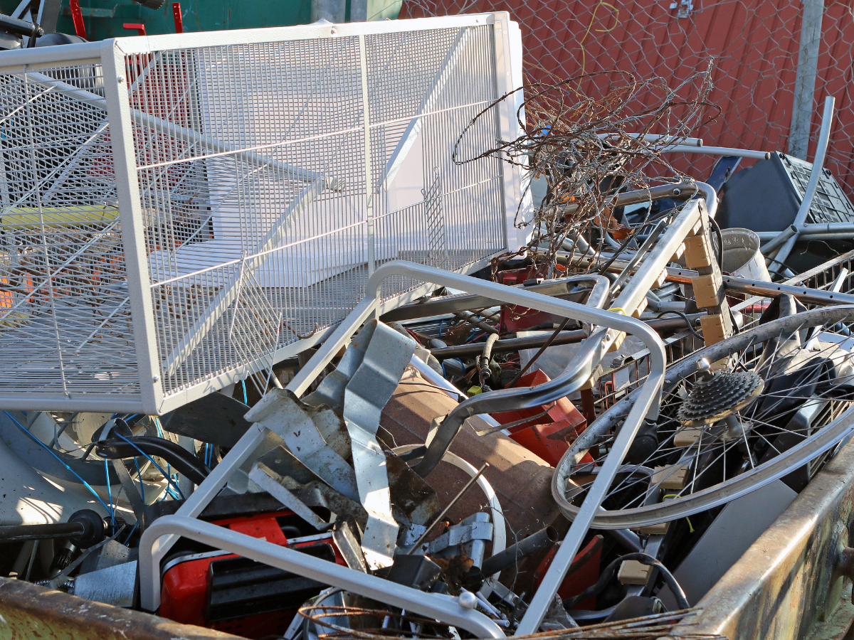 A pile of scrap metal is sitting in a dumpster.