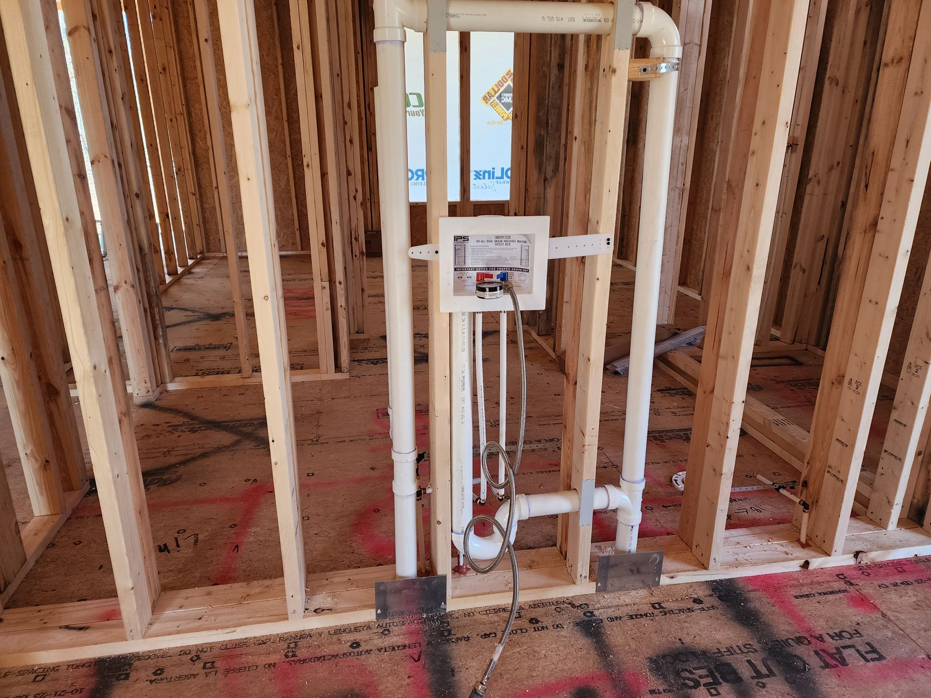 Wooden framing of a room with plumbing and electrical box installed on a stud wall.
