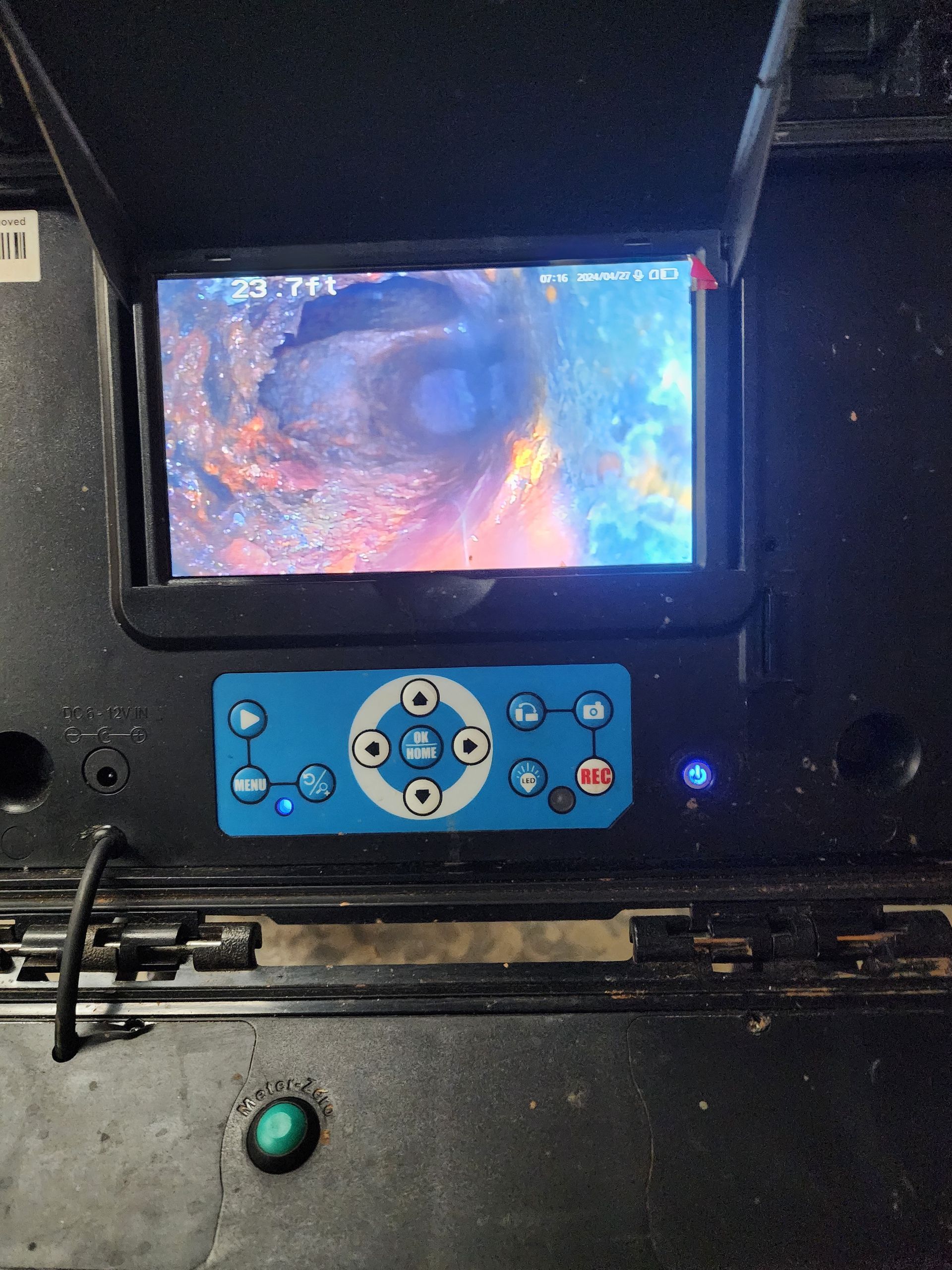 Control panel with screen displaying a swirling, colorful image. Buttons and a green light are also visible.