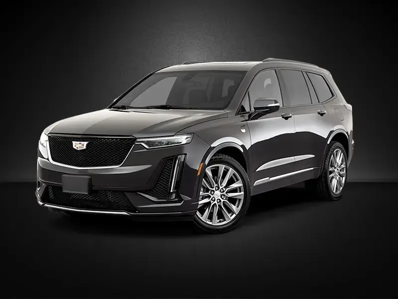 A black cadillac xt6 is parked on a black background.