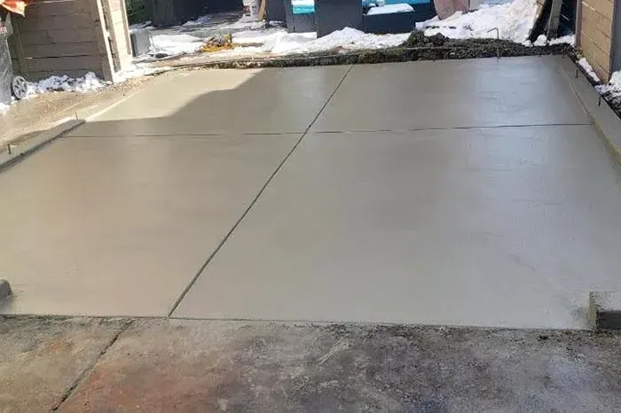 A concrete driveway is being built in the backyard of a house.