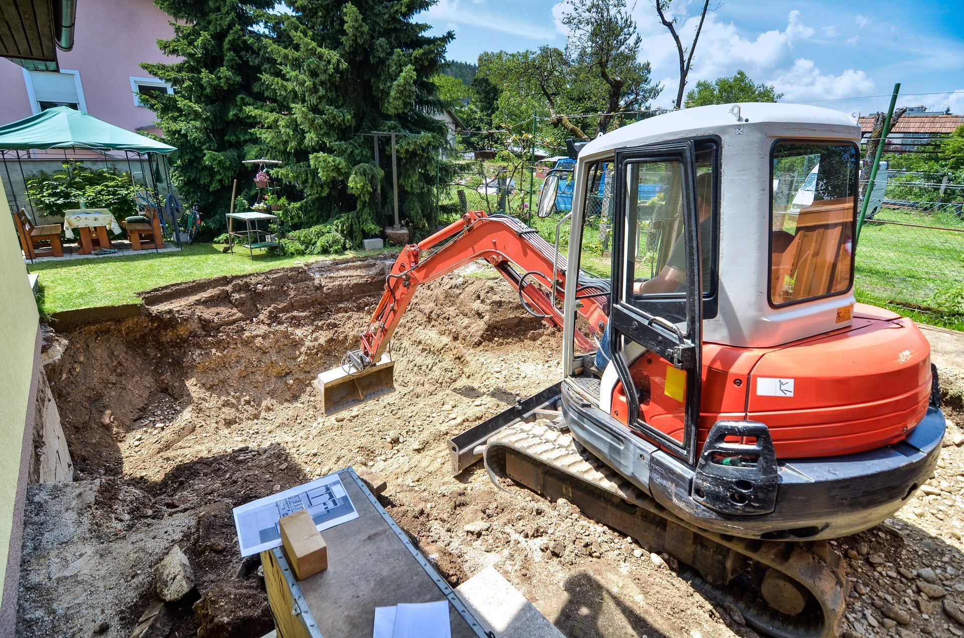 Une mini-pelle creuse dans un jardin pour des travaux de construction.