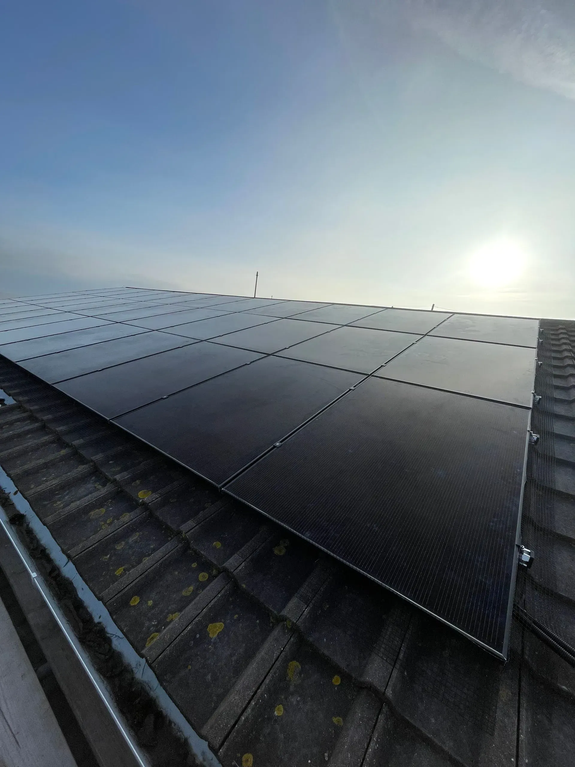Solar panels on a roof, angled toward the sun in a clear sky.