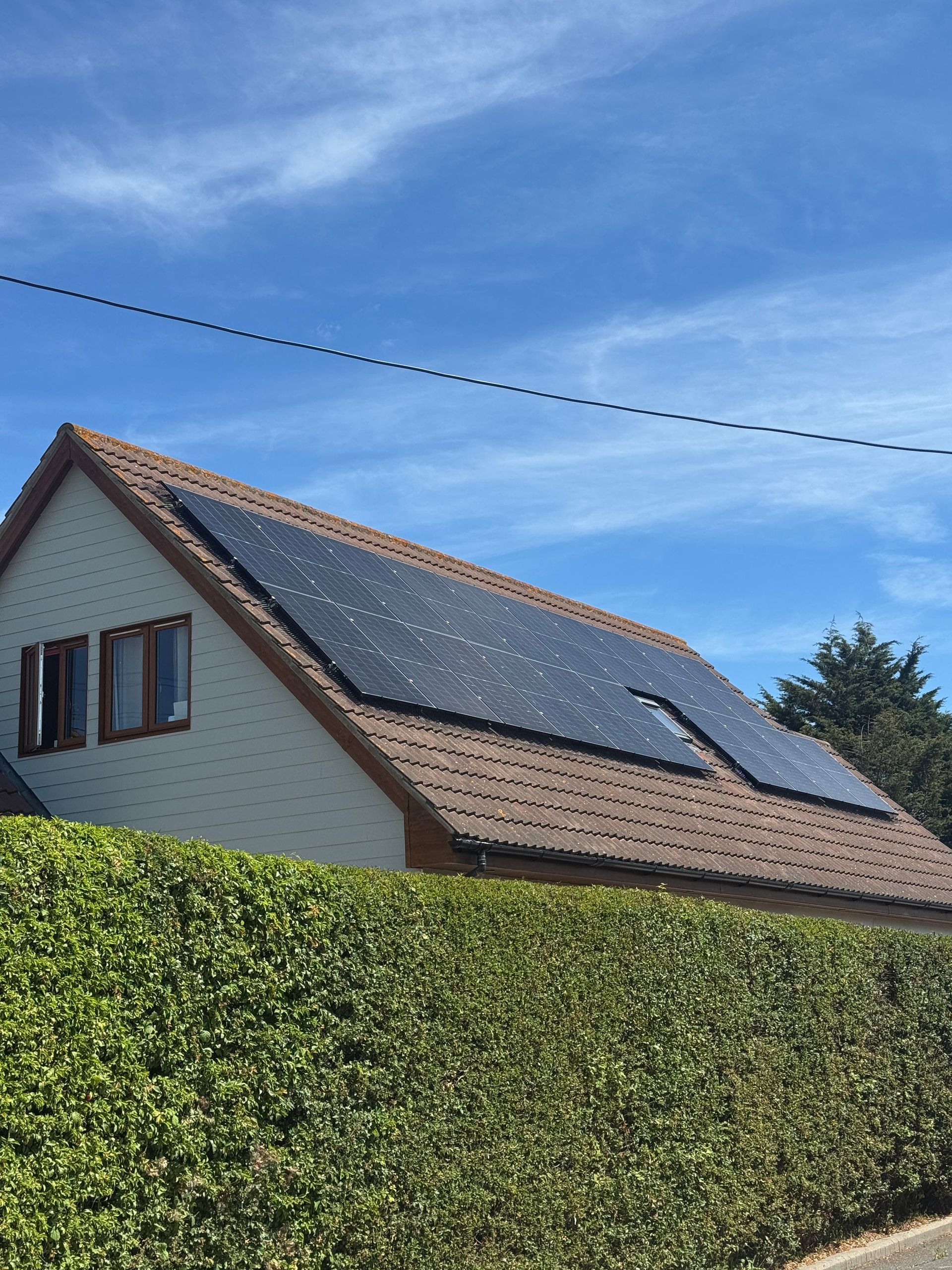 House with solar panels on roof, blue sky backdrop.