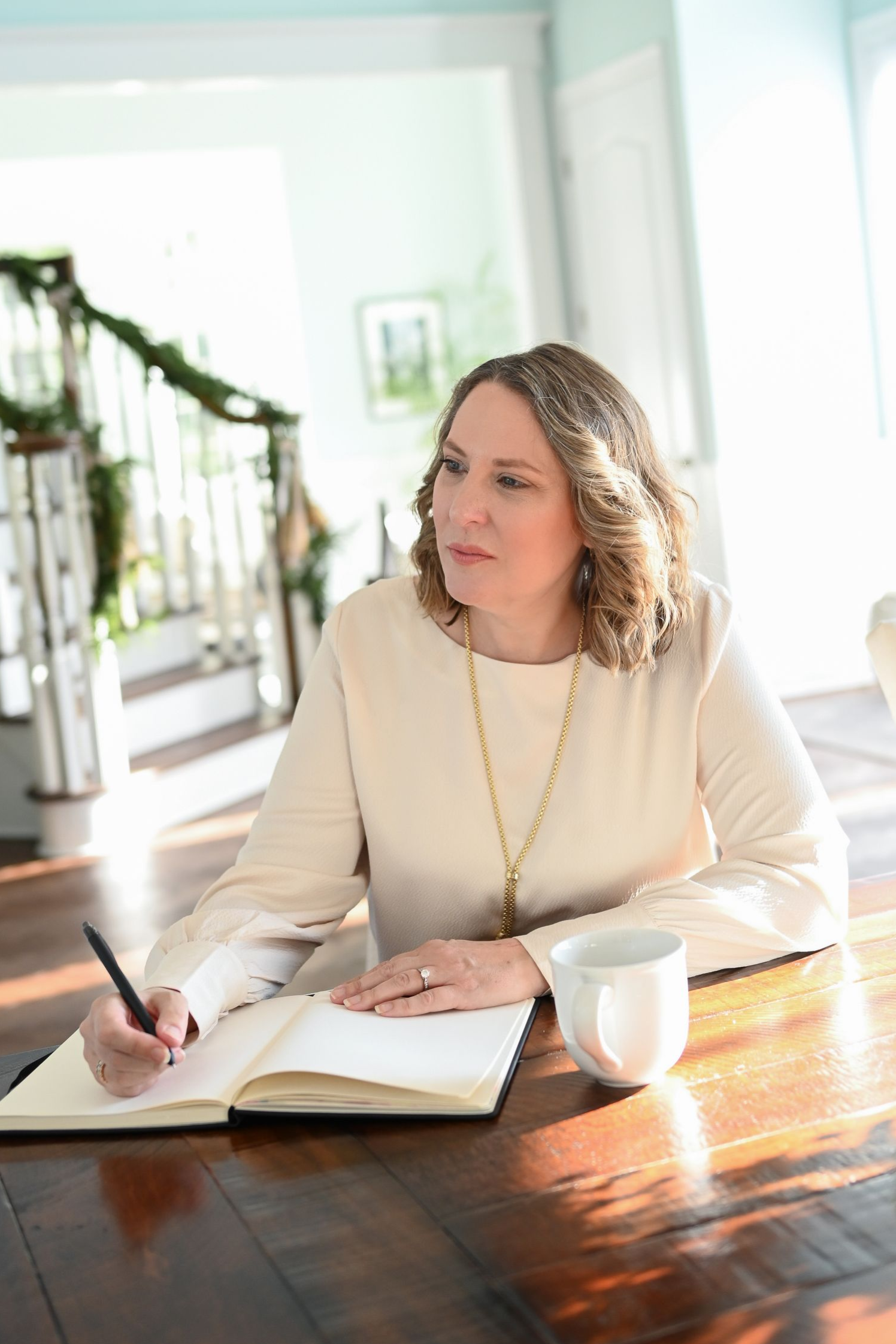 Woman smiling at the camera, wearing a rust-colored blouse, with hoop earrings in an office setting.