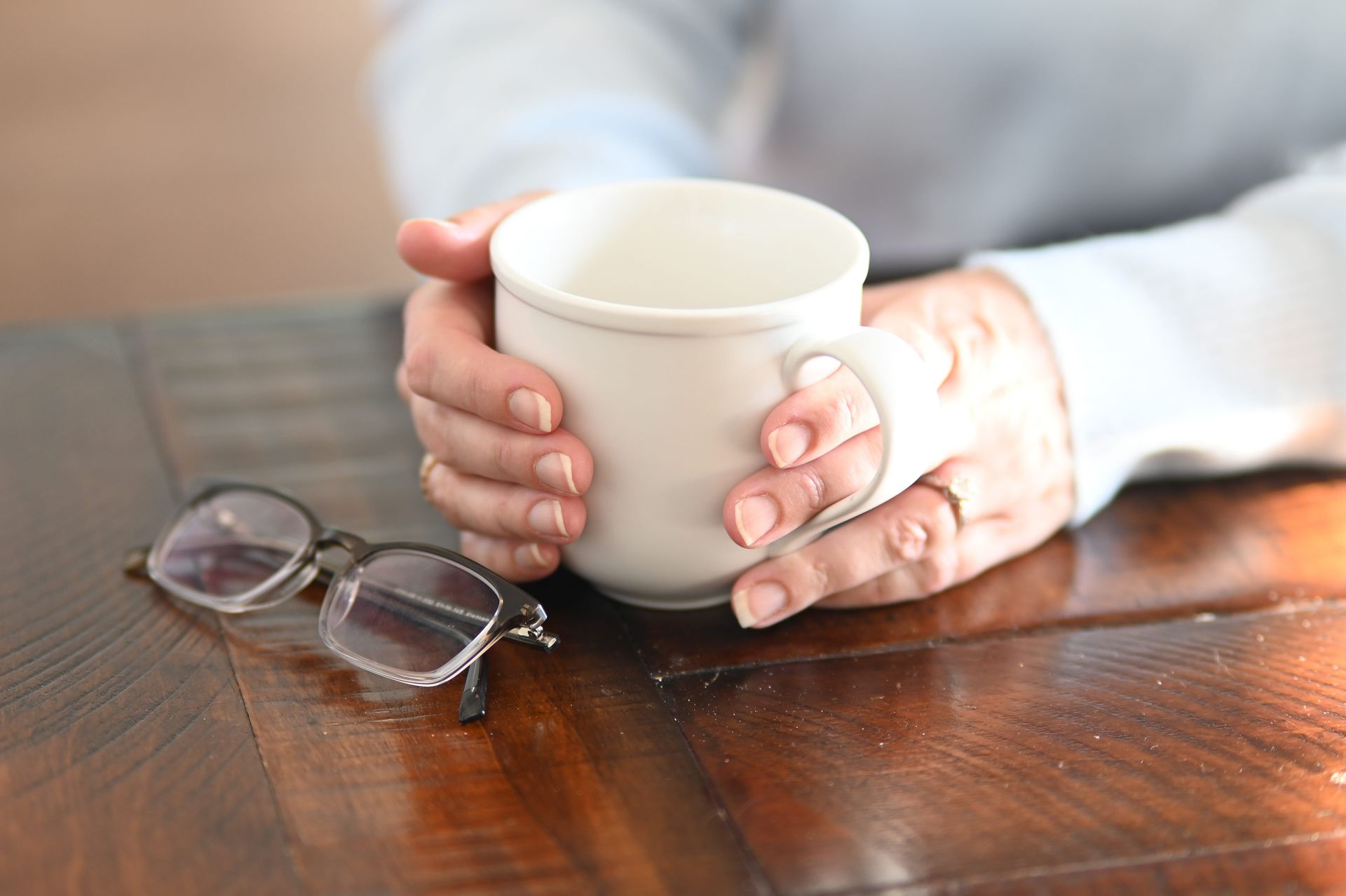 Woman smiling in front of a stone wall, wearing a maroon leather jacket and cream blouse.