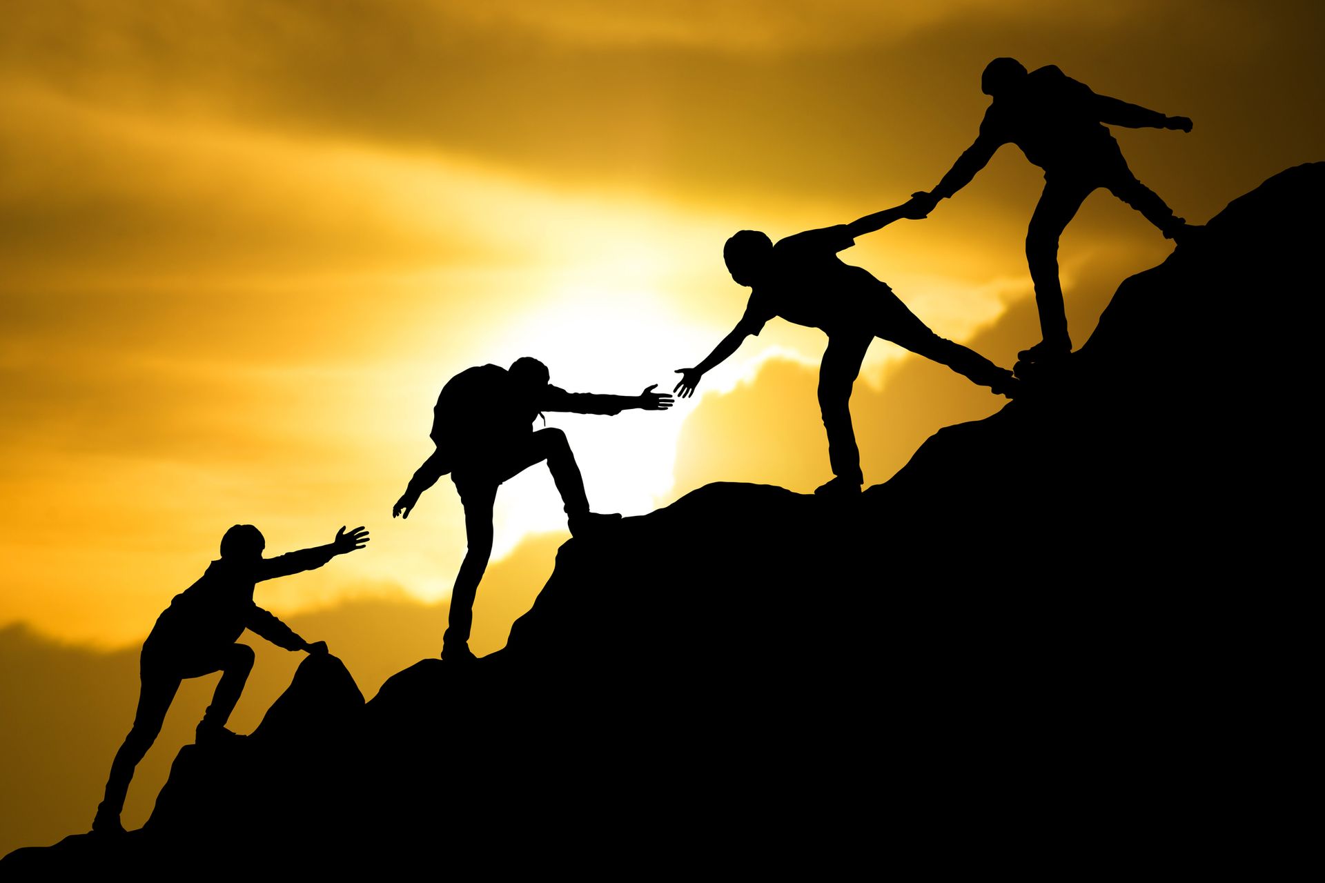 A group of people are helping each other climb a mountain.