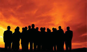 A group of people are standing in front of a sunset.