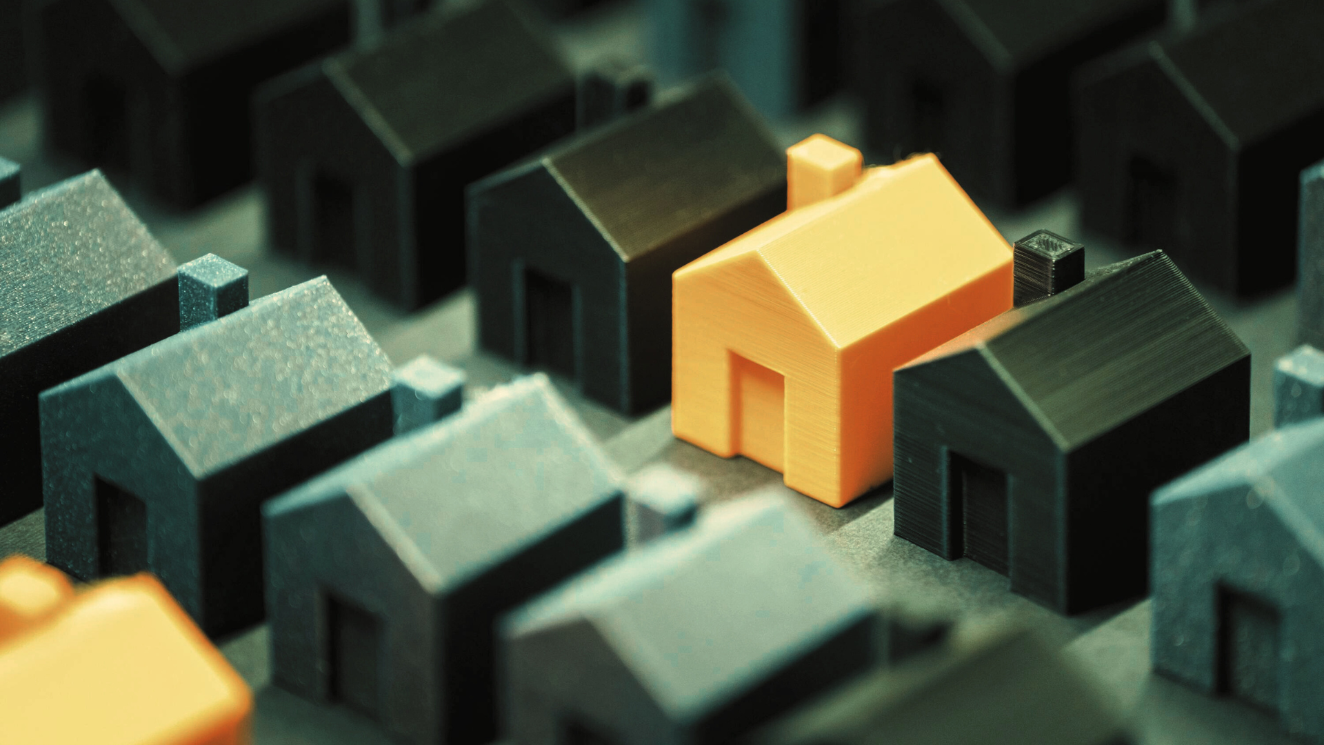 Orange modular house standing out among black houses, symbolising growth and demand for modular cons