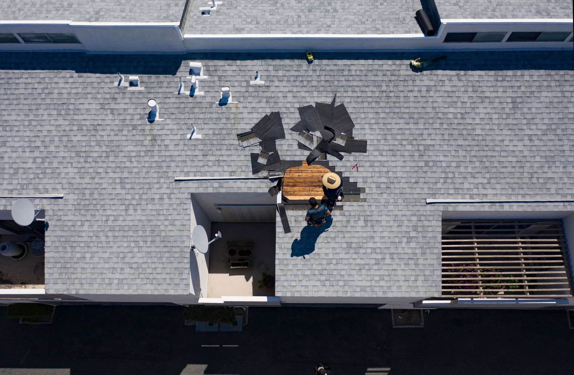 Aerial view of roofers on condo, showcasing commercial roof repair