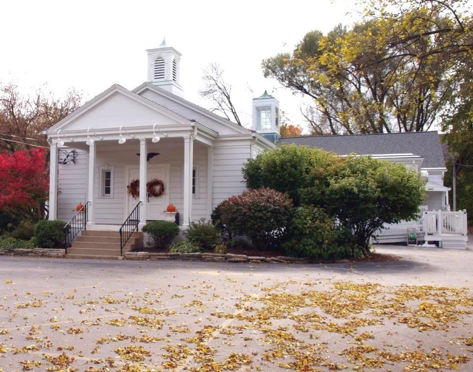 A white house with a porch and a clock tower
