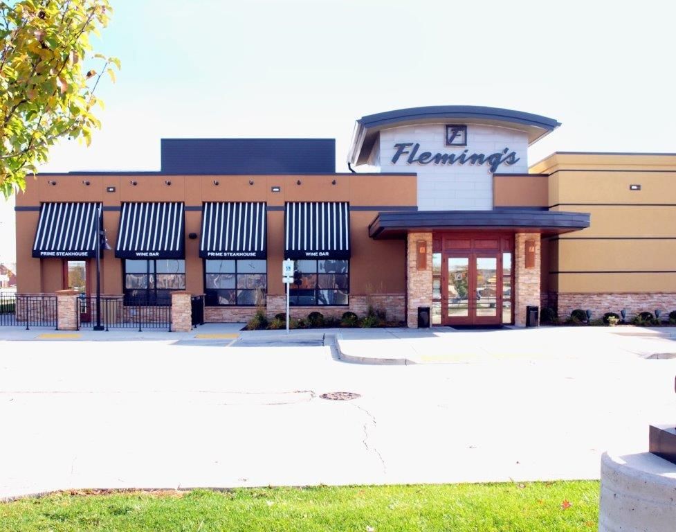 A restaurant called fleming 's has striped awnings on the windows