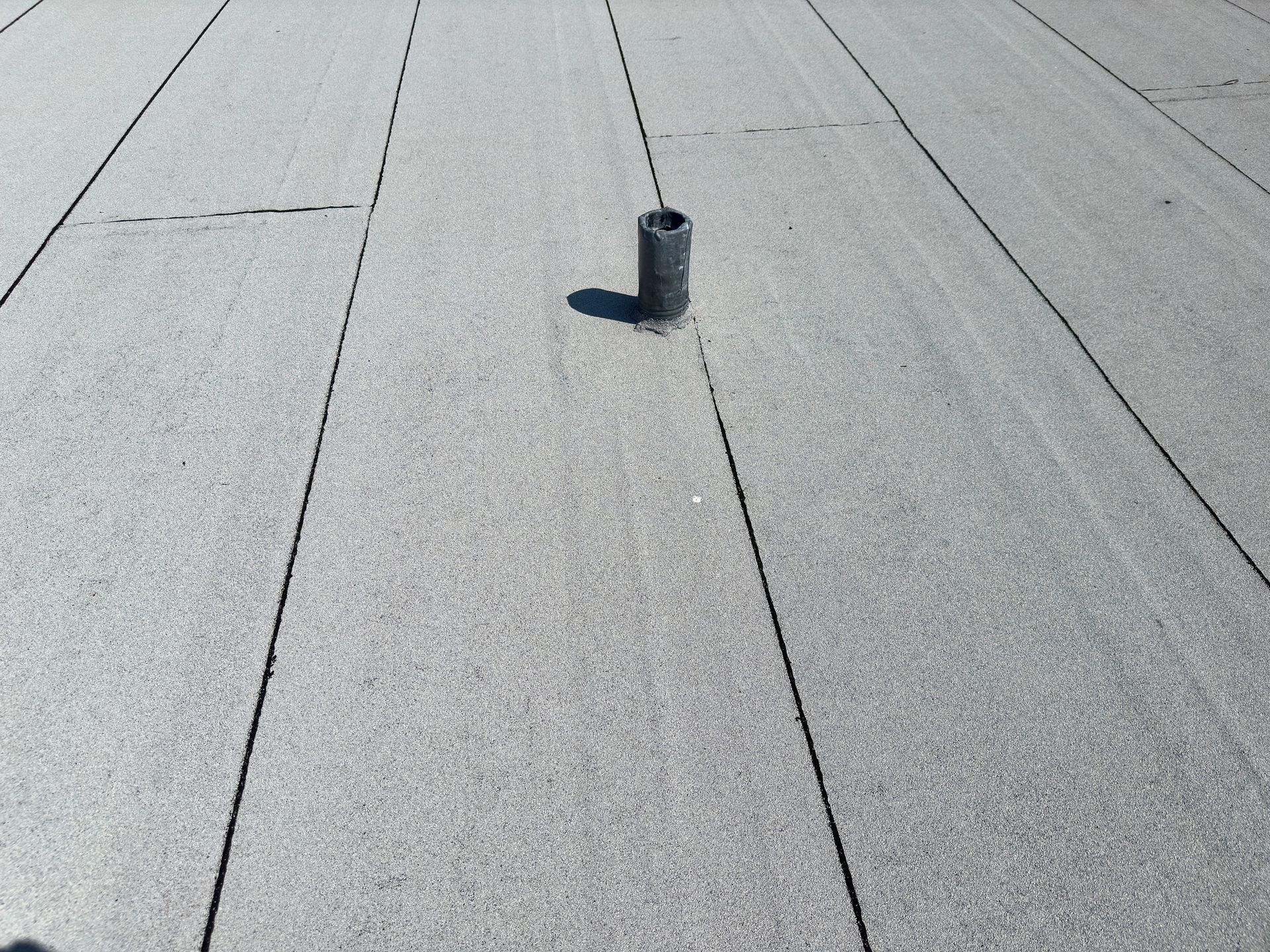 View of a commercial flat roof with a sewer vent pipe.