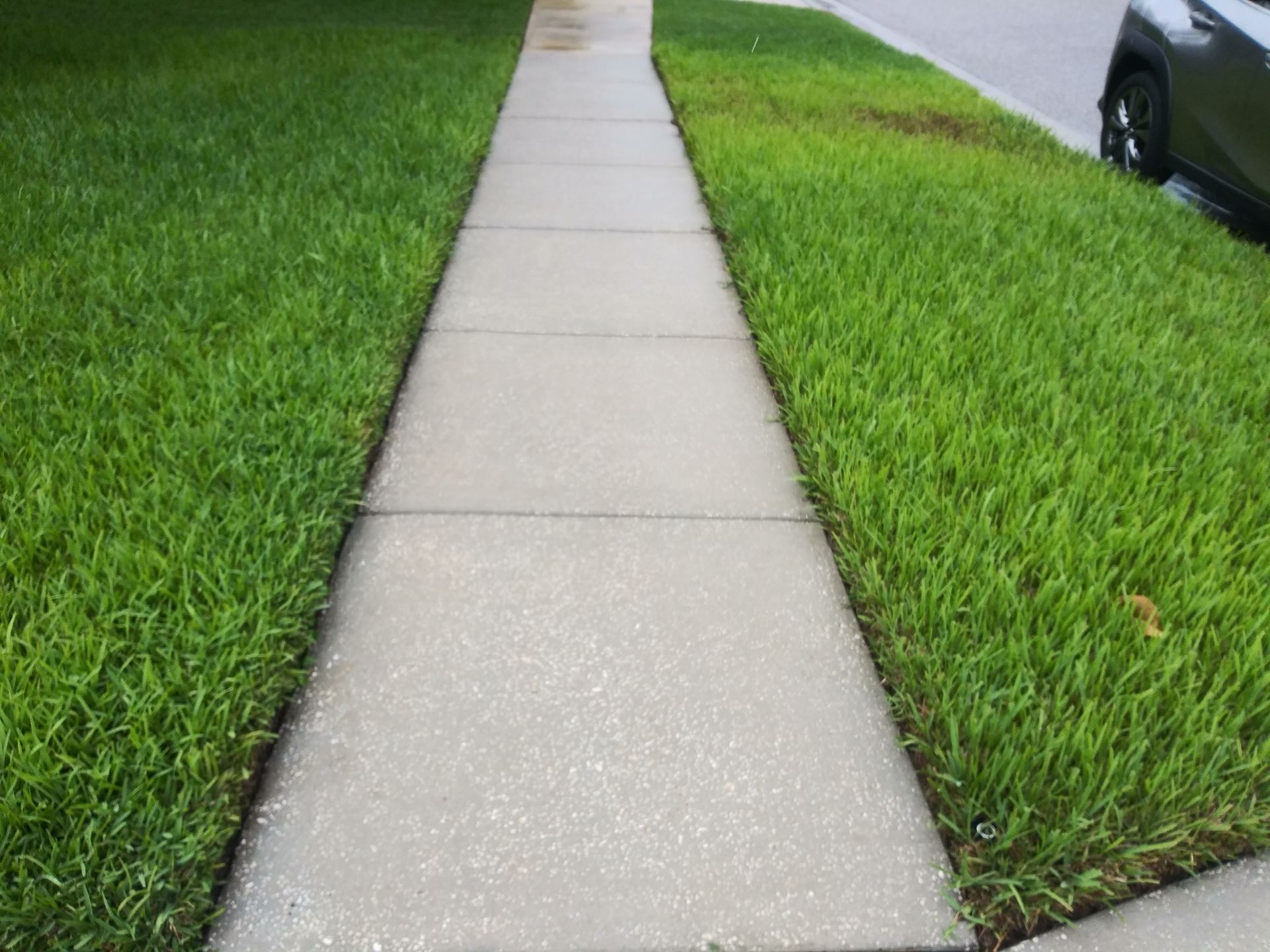 A sidewalk with a car parked on the side of it