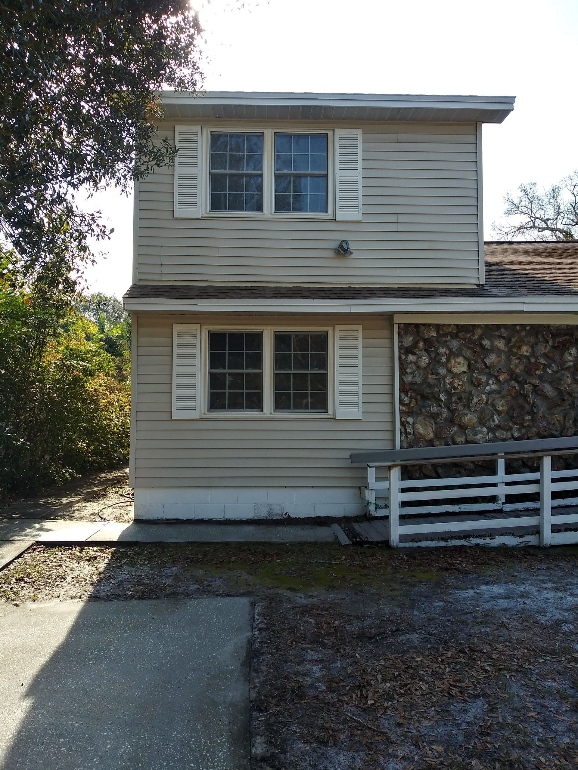 A house with a stone wall and shutters on the windows