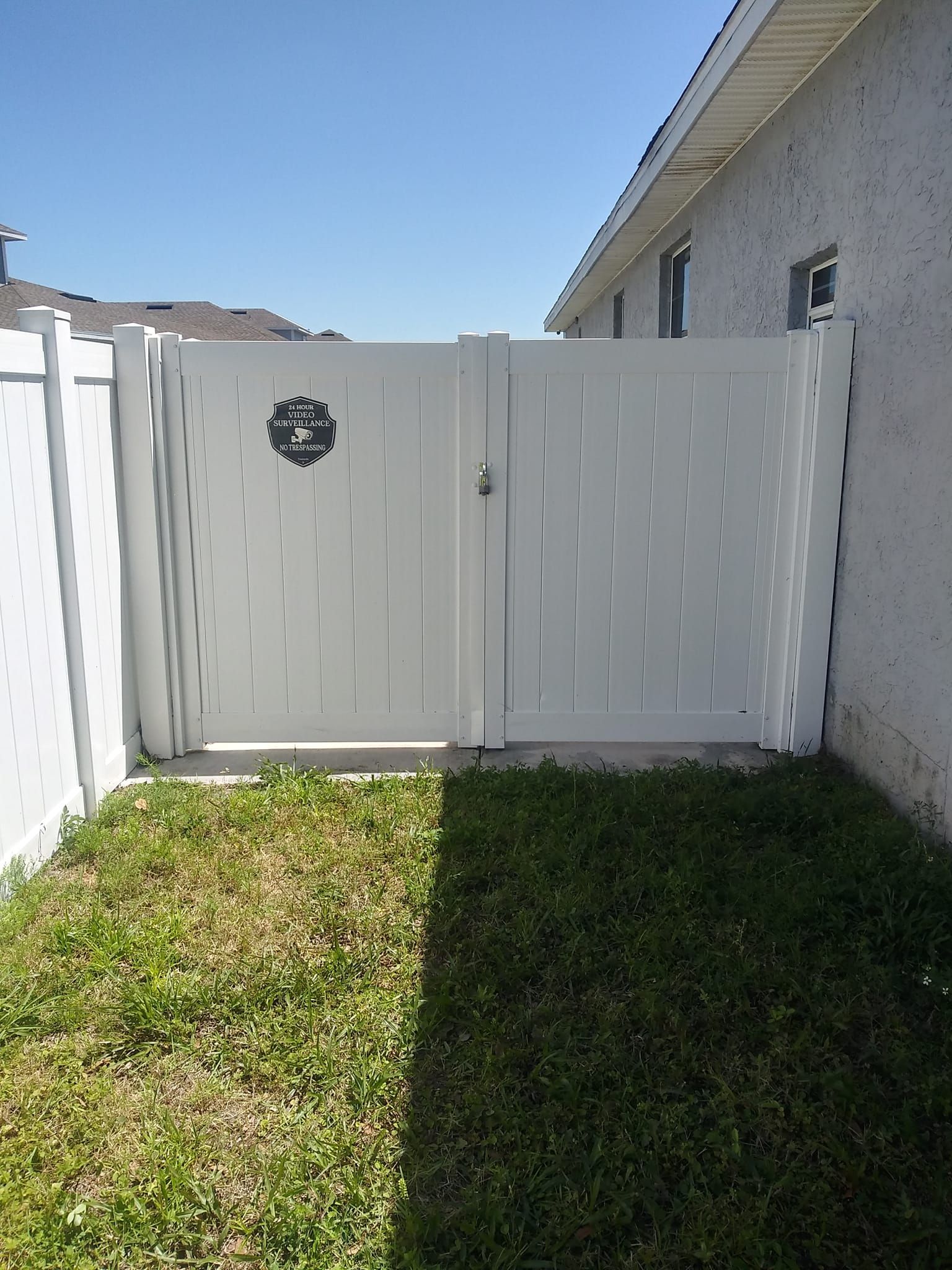A white gate with a wreath on it is in the backyard of a house.