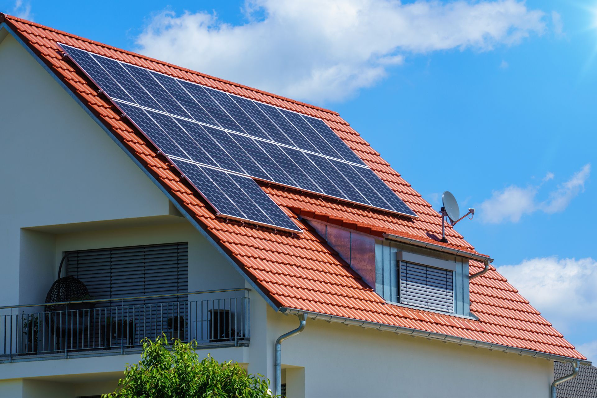 House with solar panels on the roof against a blue sky.