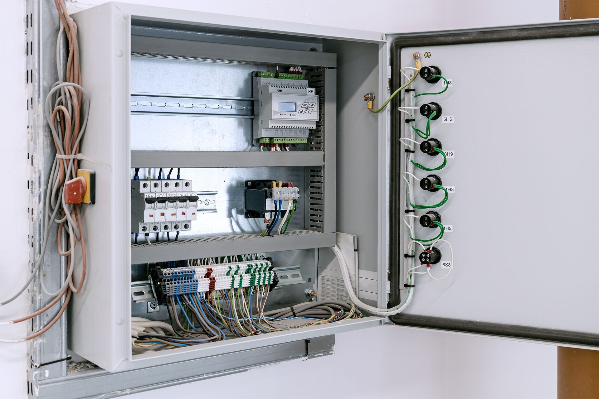 Electrical control panel with open door, displaying wiring and components.