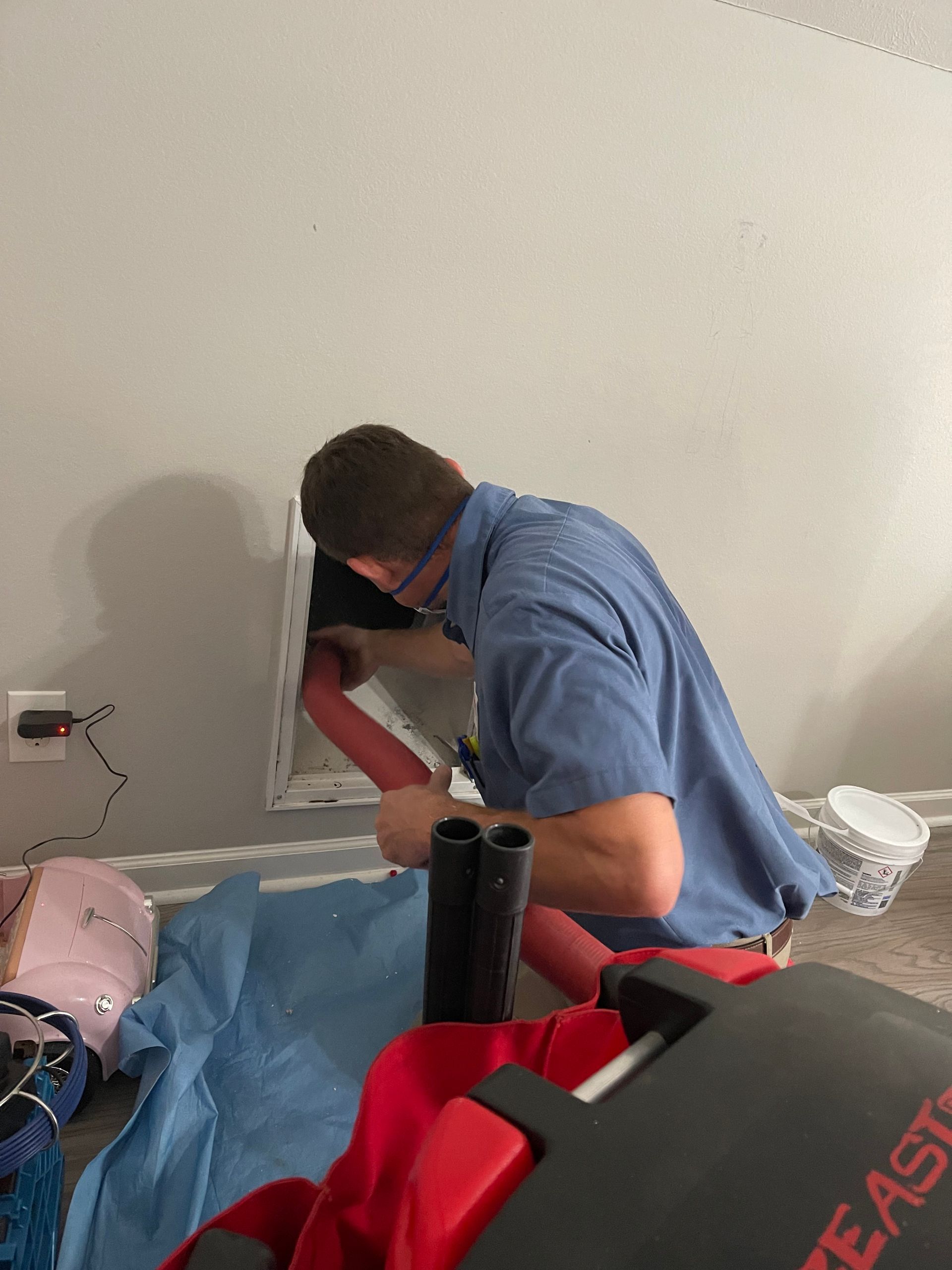 A man in a blue shirt is working on a hole in a wall.