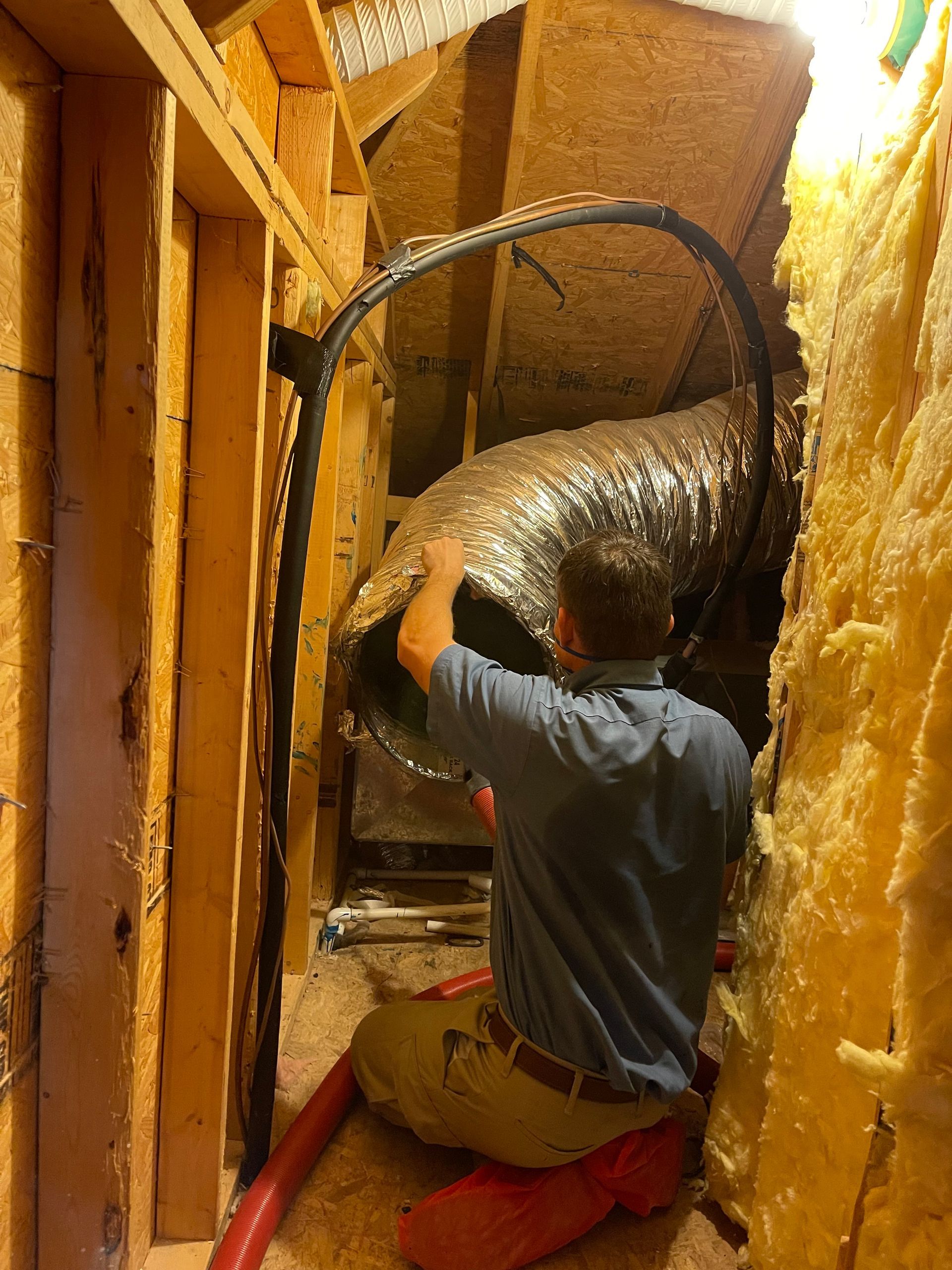 A man is kneeling down in a room holding a large hose