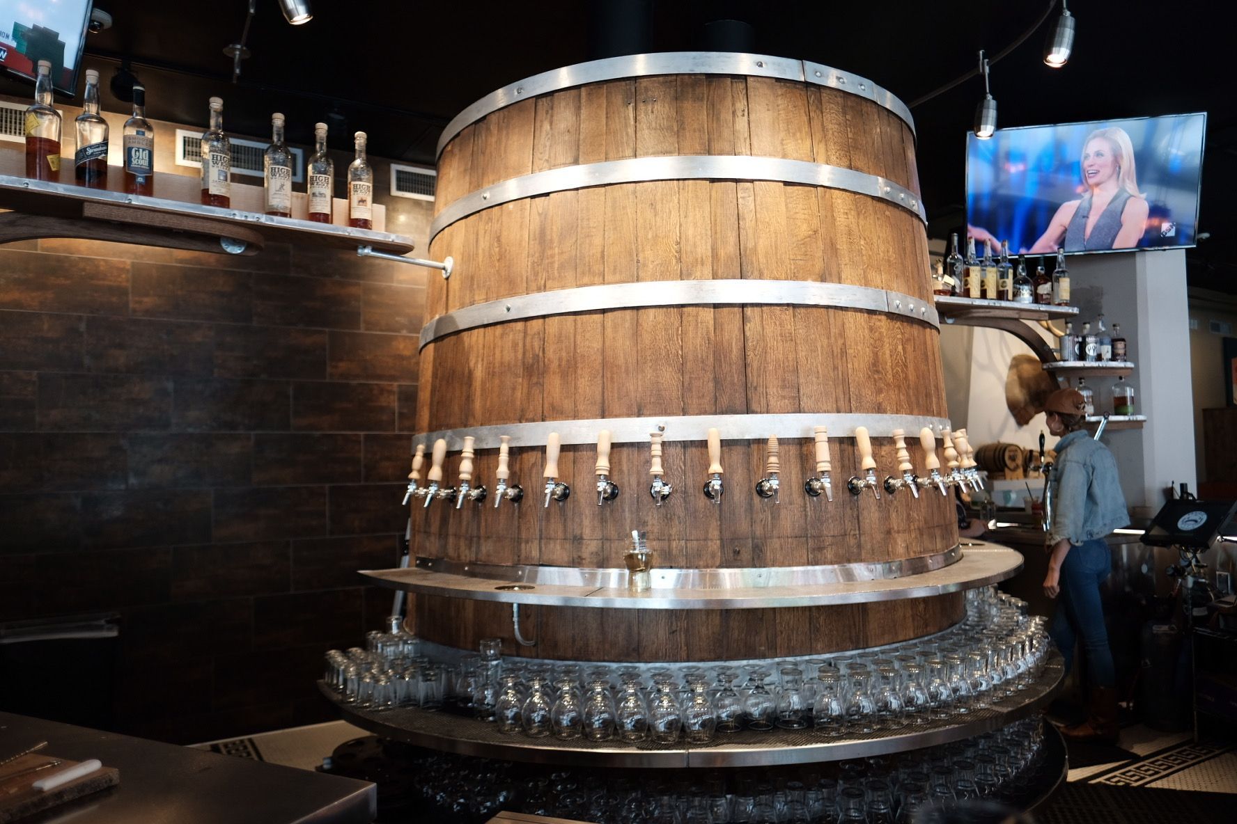 Large wooden beer barrel with multiple taps in a bar setting.
