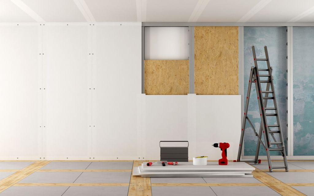 Partially renovated room with white drywall, exposed insulation, ladder, and tools on the floor.