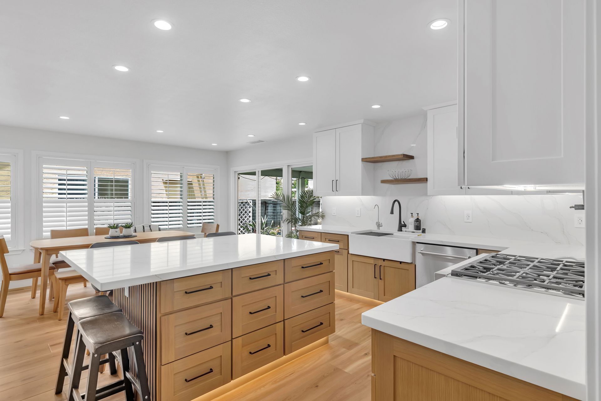 Modern kitchen with white countertops, light wood cabinets, and large island with seating.