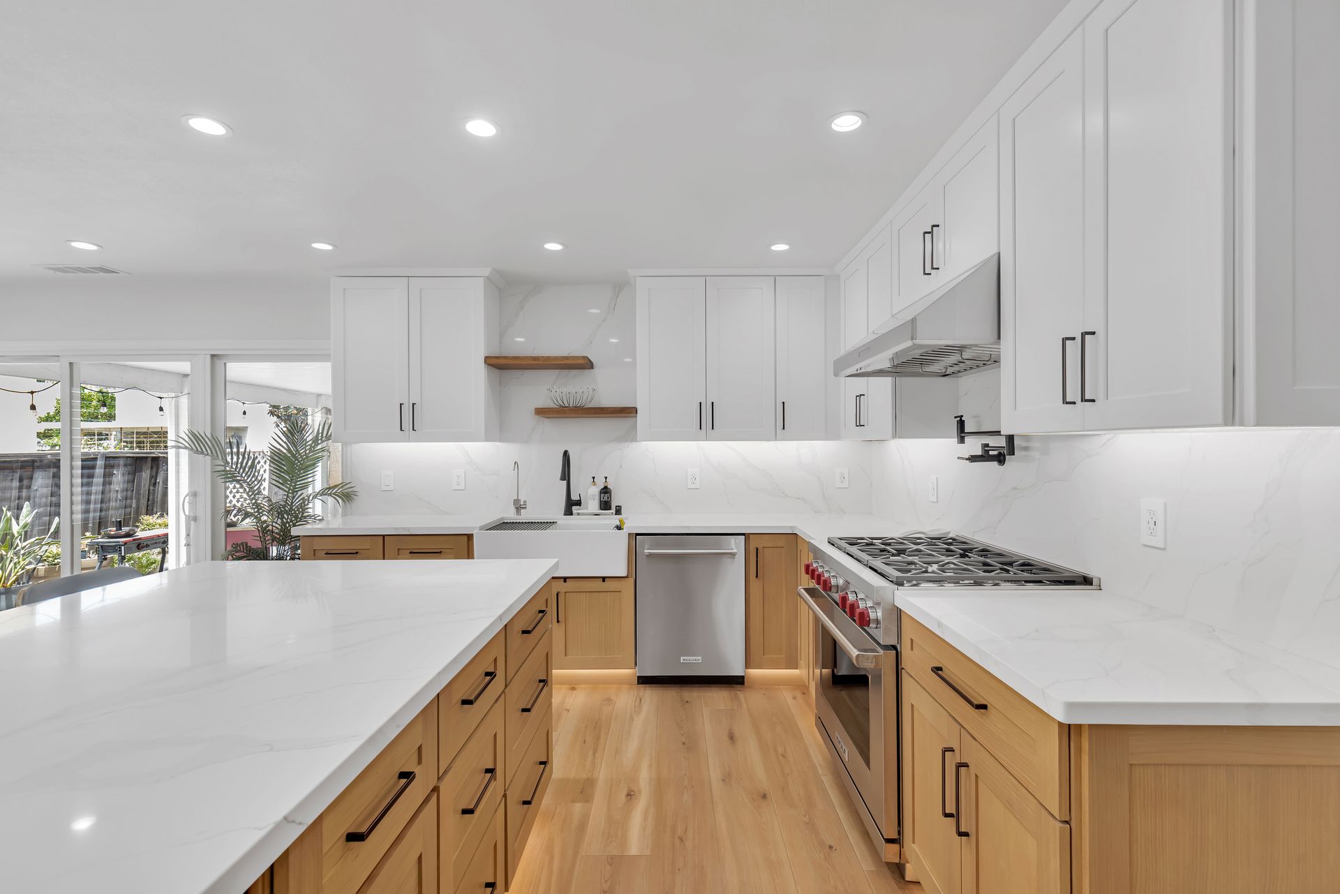 Modern kitchen with white and wood cabinets, quartz countertops, stainless steel appliances, and a large island.