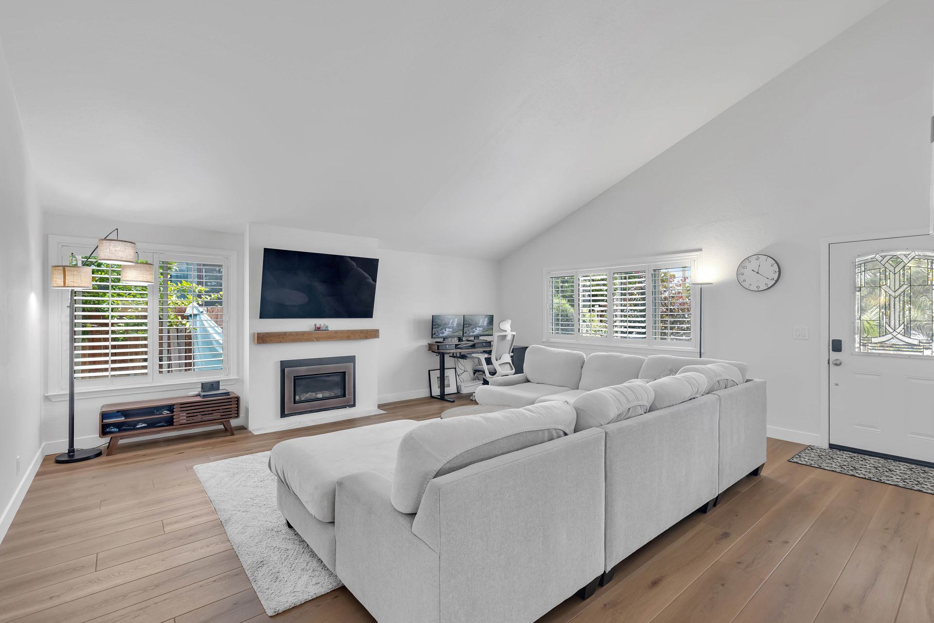 Modern kitchen with light wood cabinetry, white countertops, and two windows.