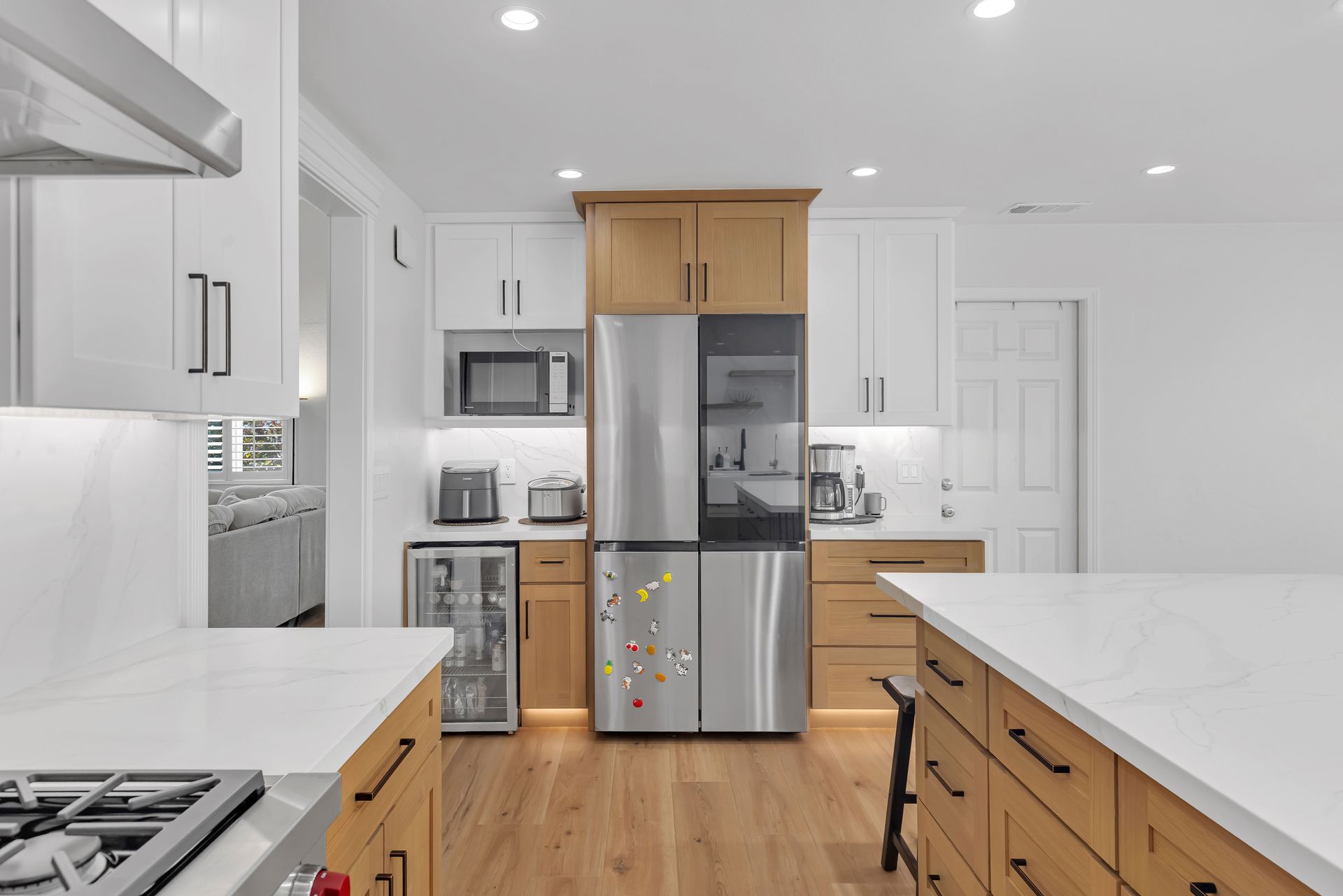 Modern kitchen with stainless steel appliances, light wood cabinets, and white countertops.