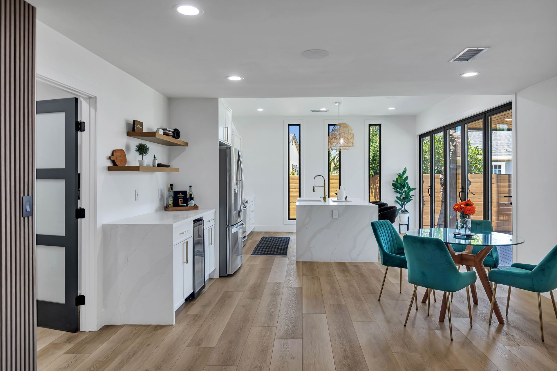 Modern kitchen with marble countertops, wood cabinets, stainless steel appliances, and pendant lighting.