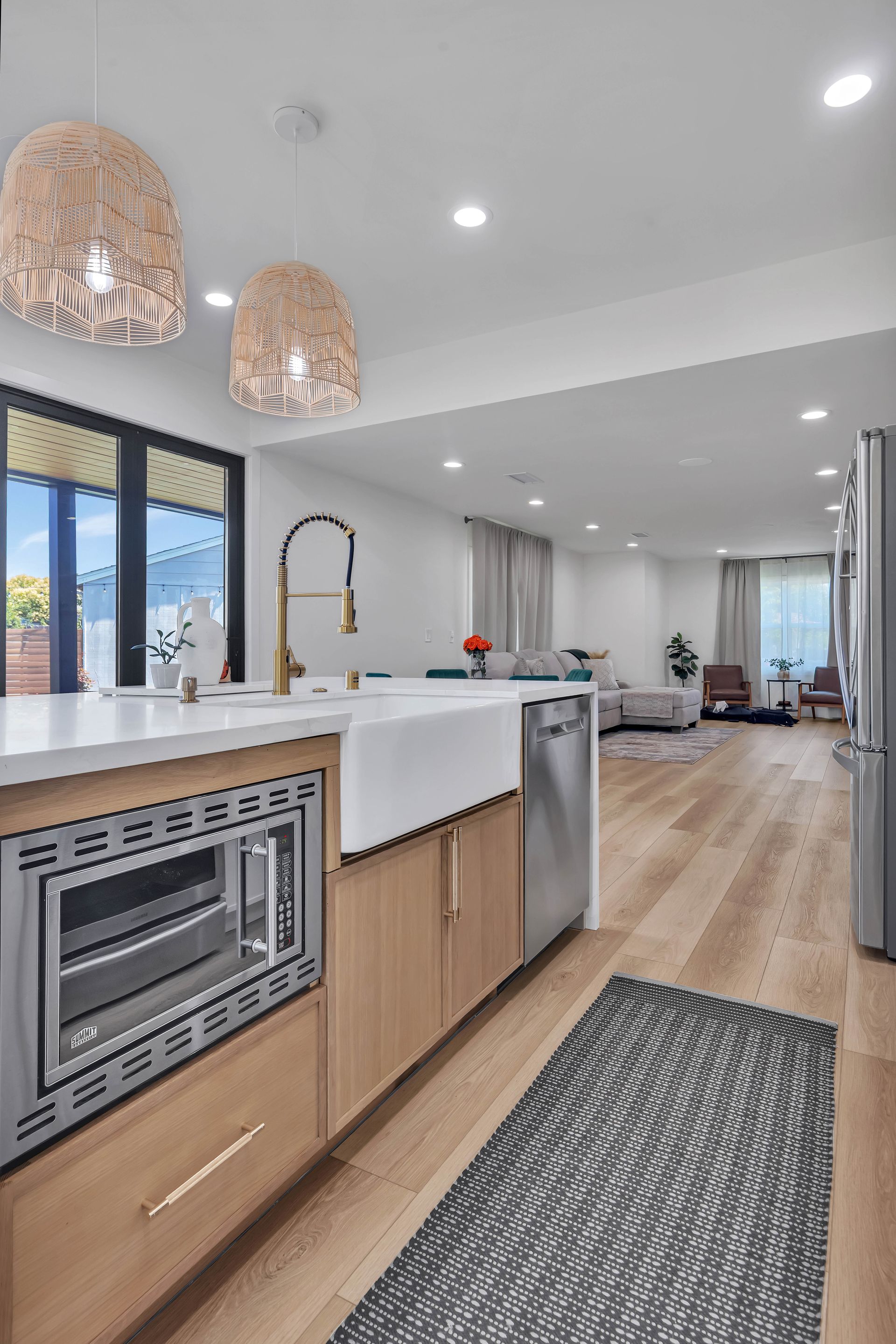 Bathroom with a wooden vanity, illuminated mirror, and a window.
