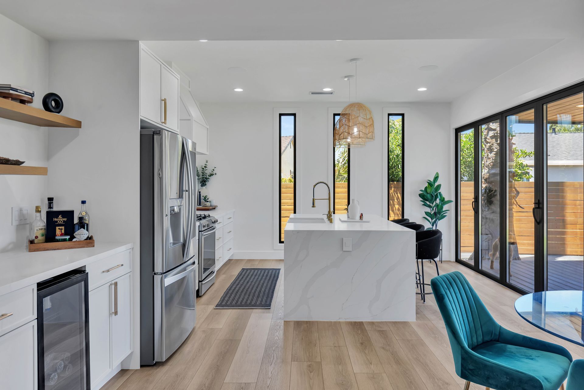 Modern kitchen with white cabinets, stainless steel appliances, and island with quartz countertop, overlooking patio.