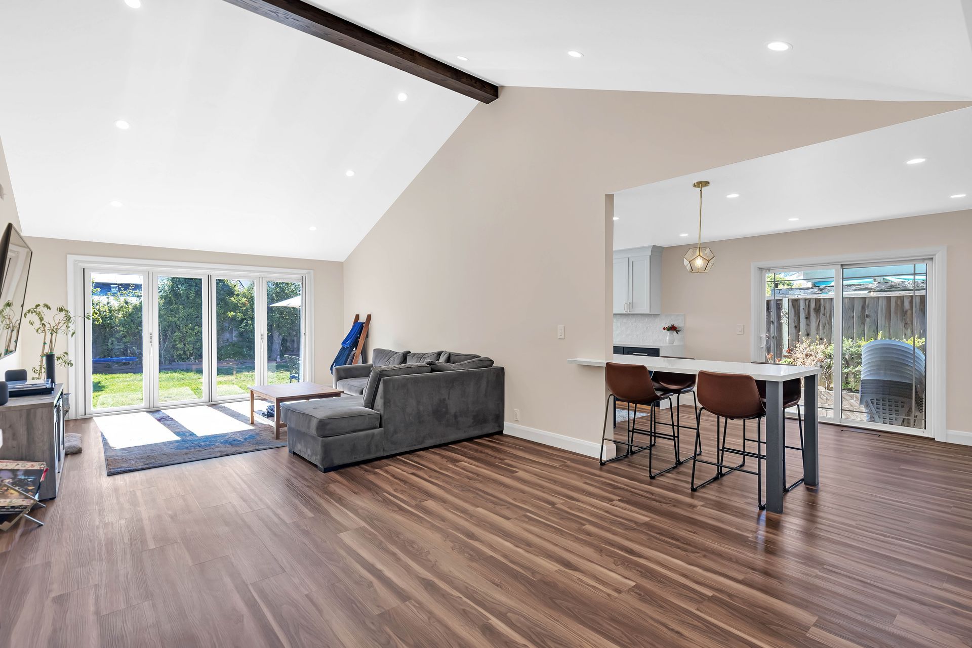 Spacious living room with vaulted ceiling, open to a kitchen. Sliding glass doors lead to a backyard.