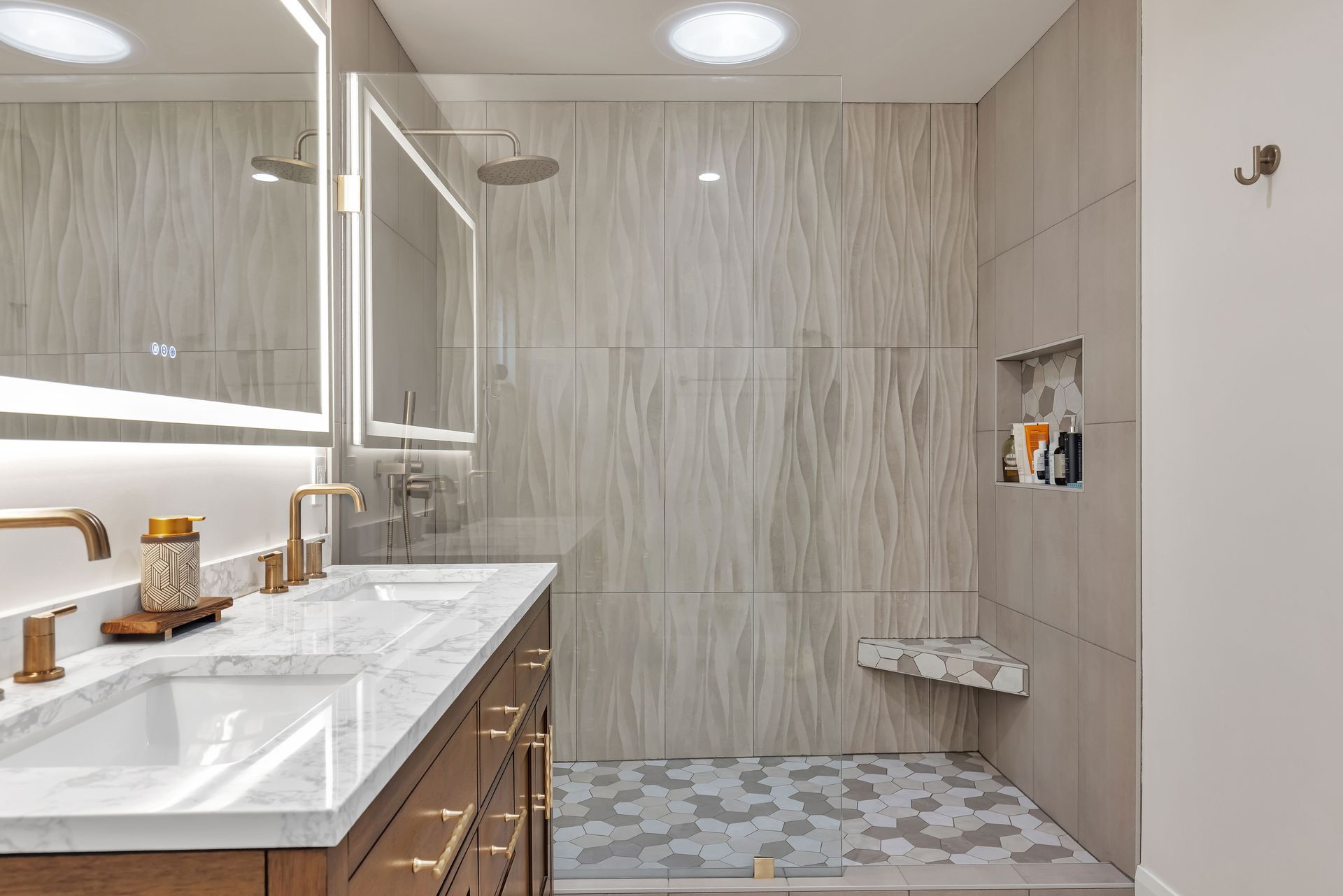 Modern bathroom with marble countertops, wood vanity, and a tiled walk-in shower.