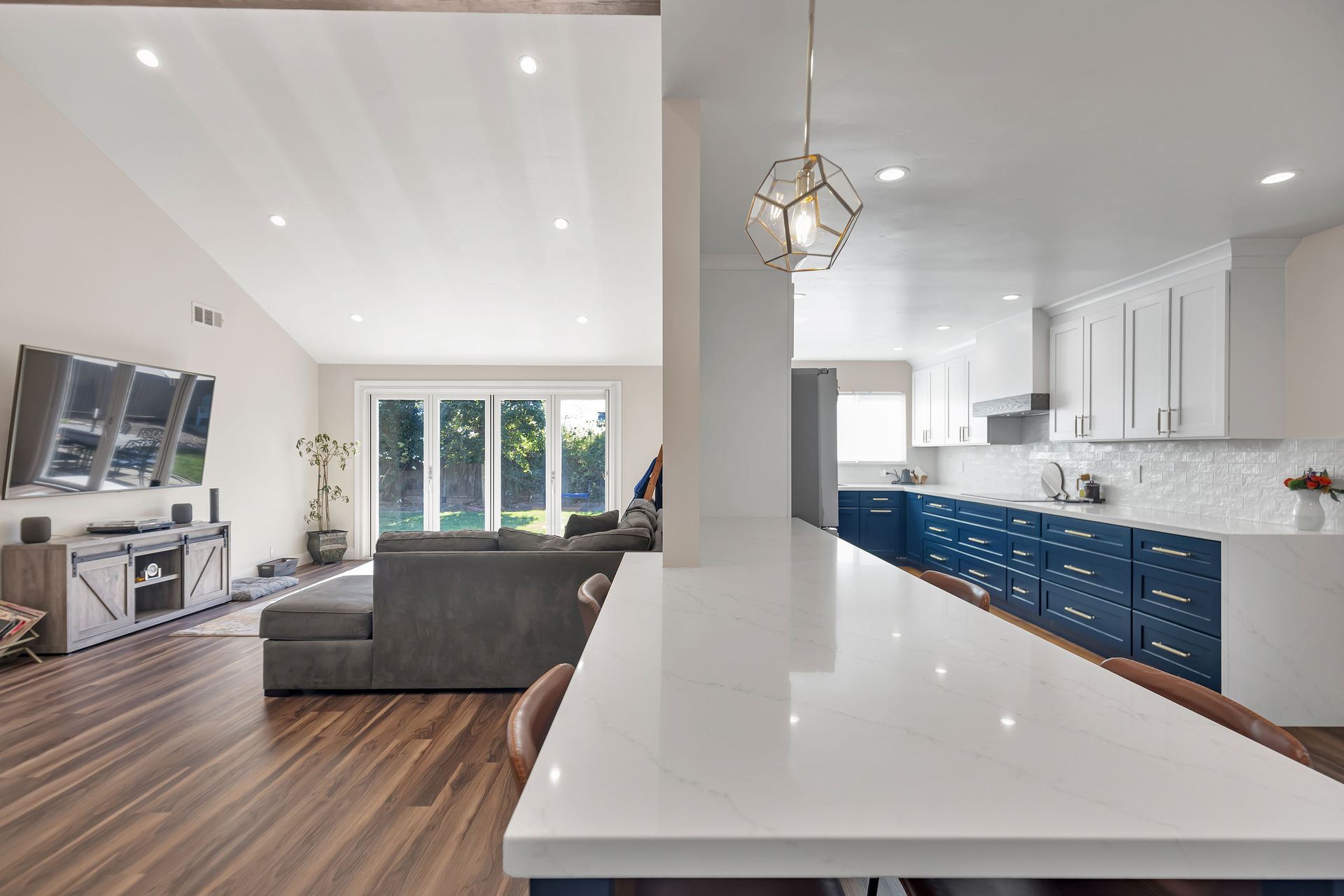 Modern gray-tiled shower with glass door, black fixtures, built-in bench, and small window.