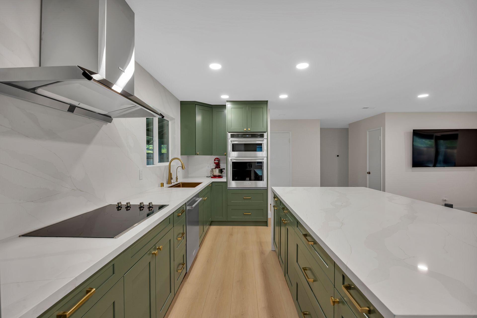 Modern kitchen with green cabinets, white countertops, and a large island.