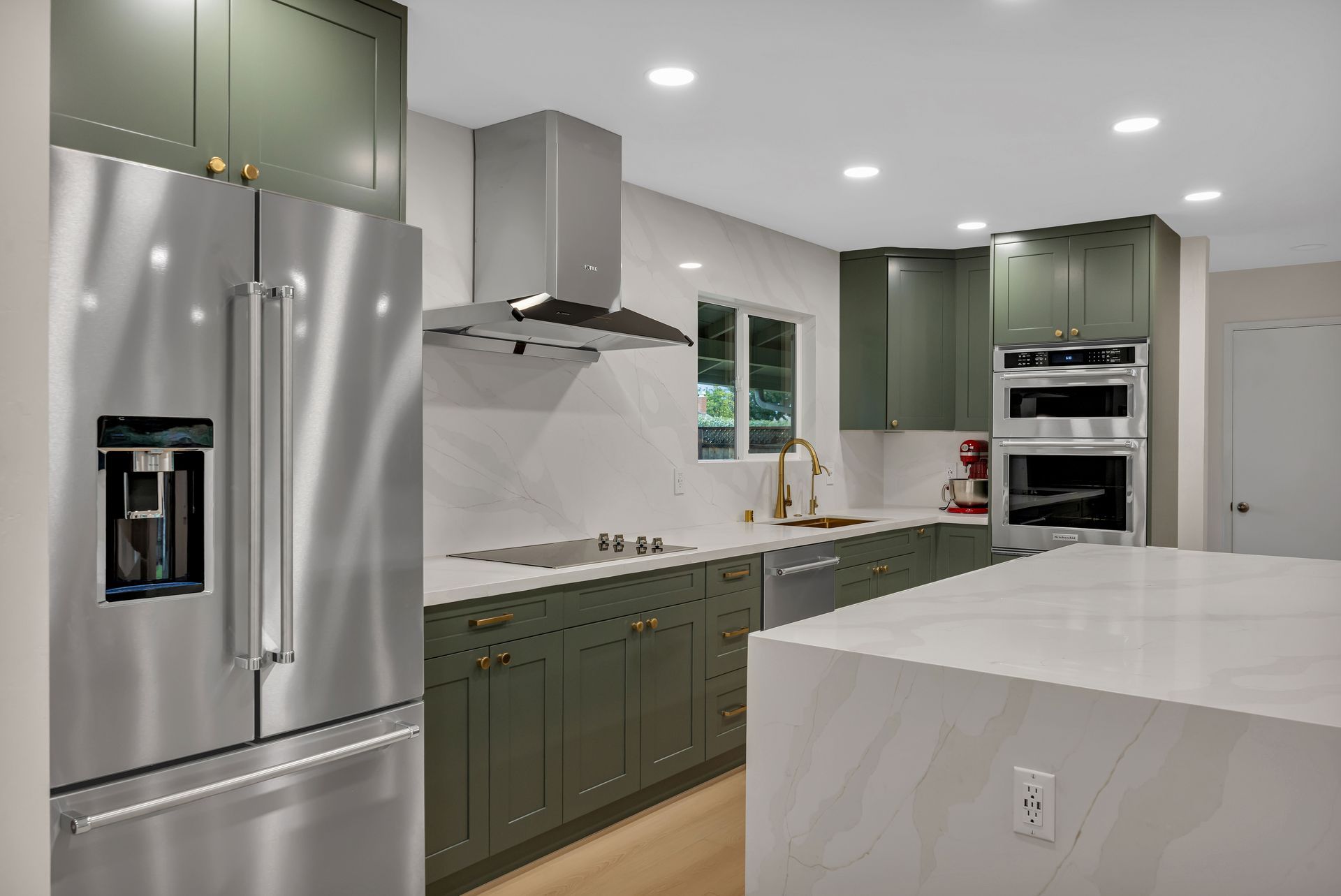 Modern kitchen with olive green cabinets, stainless steel appliances, and white countertops.