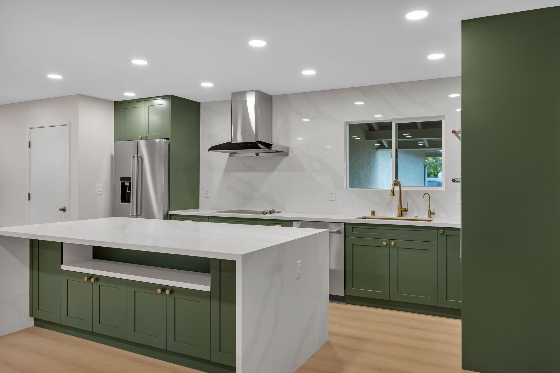 Modern kitchen with light wood cabinets, marble backsplash, and a light-colored sofa.