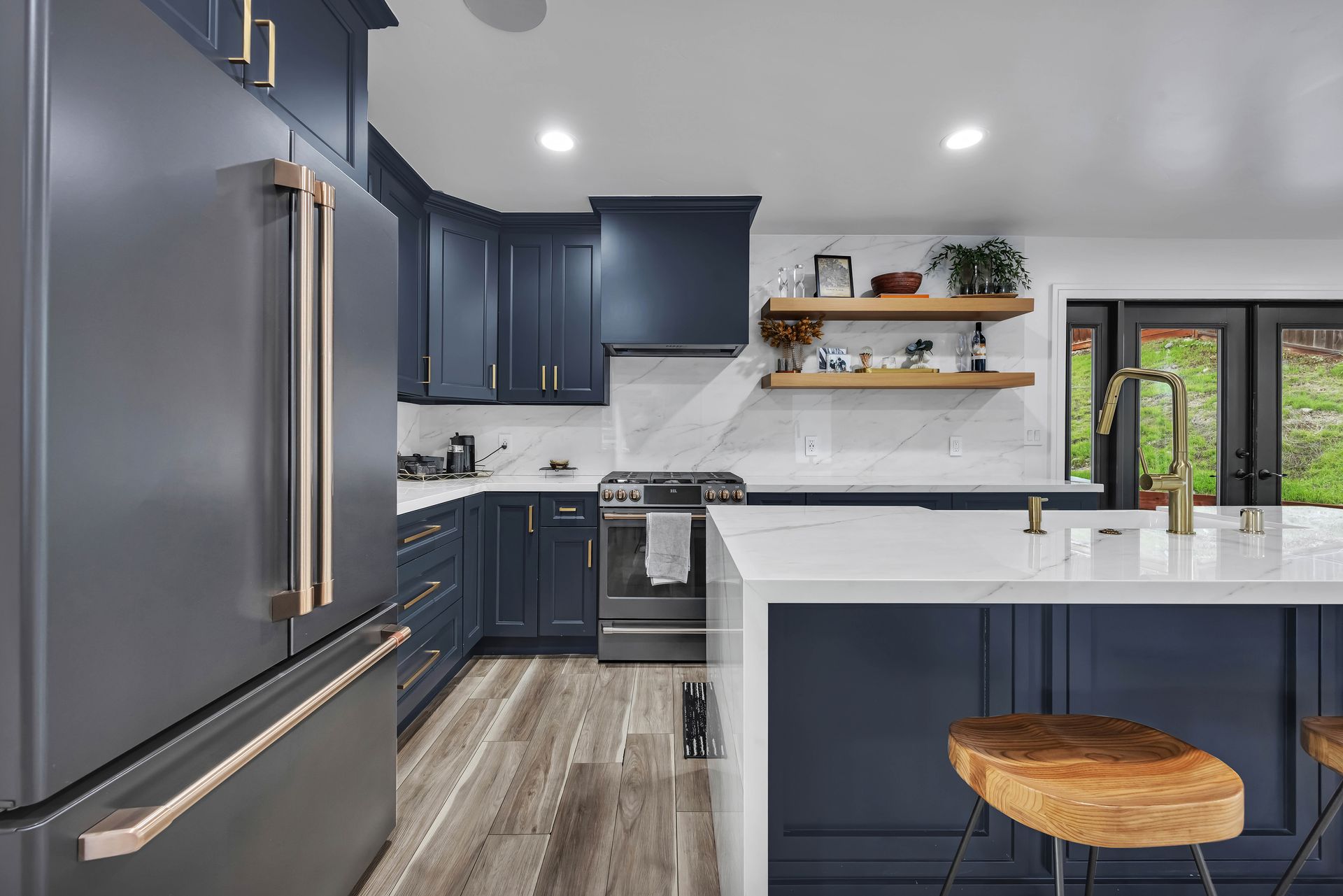 Modern kitchen with navy cabinets, white countertops, and wooden stools.