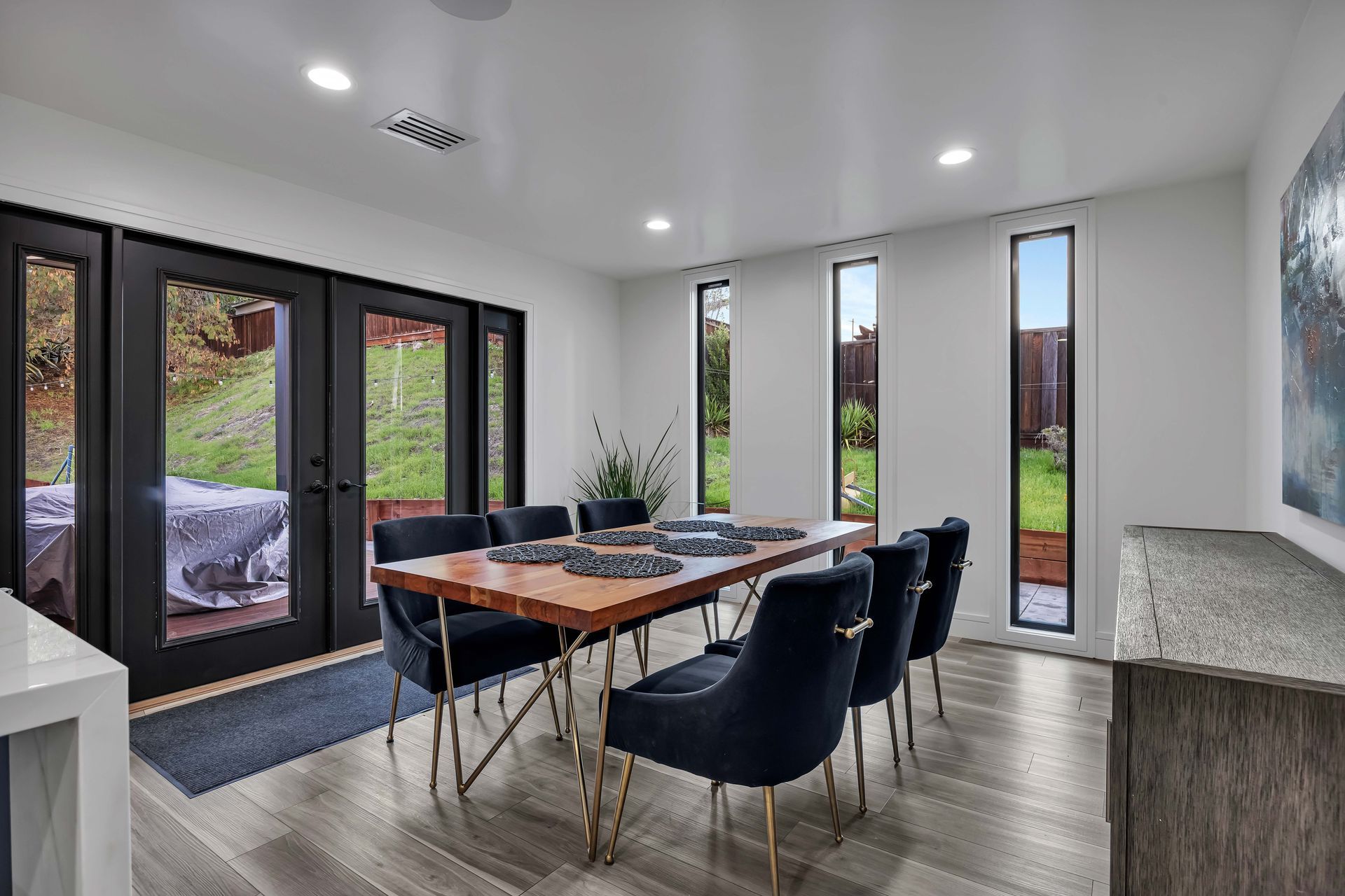 Modern bathroom with wood vanity, white countertop, and arched mirror with backlighting.