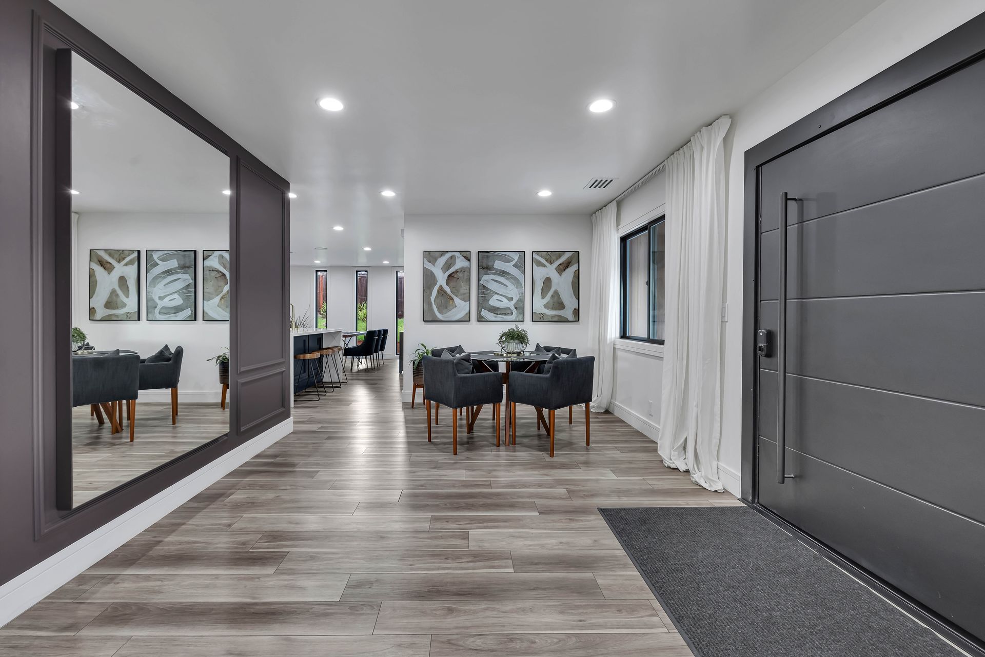 Modern kitchen with light wood cabinetry, white countertops, and two windows.