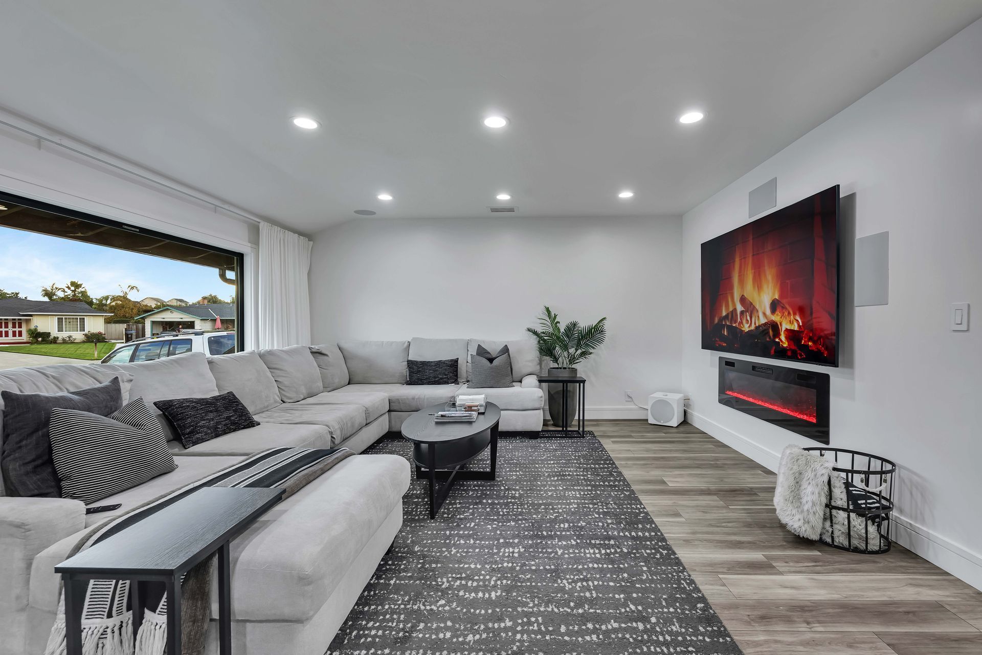 Modern living room with sectional sofa, fireplace, and TV on a white wall.