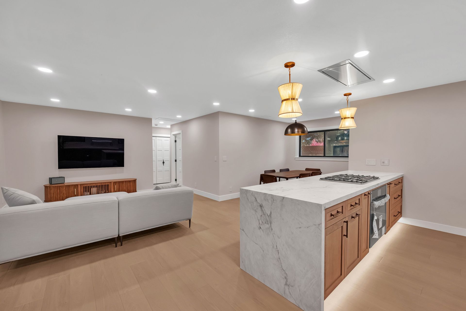 Open-concept kitchen and living area with a white sofa, island, and dining table.